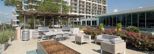 Daytime view of grill stations and tables and chairs and other seating at AMLI Design District apartment building rooftop