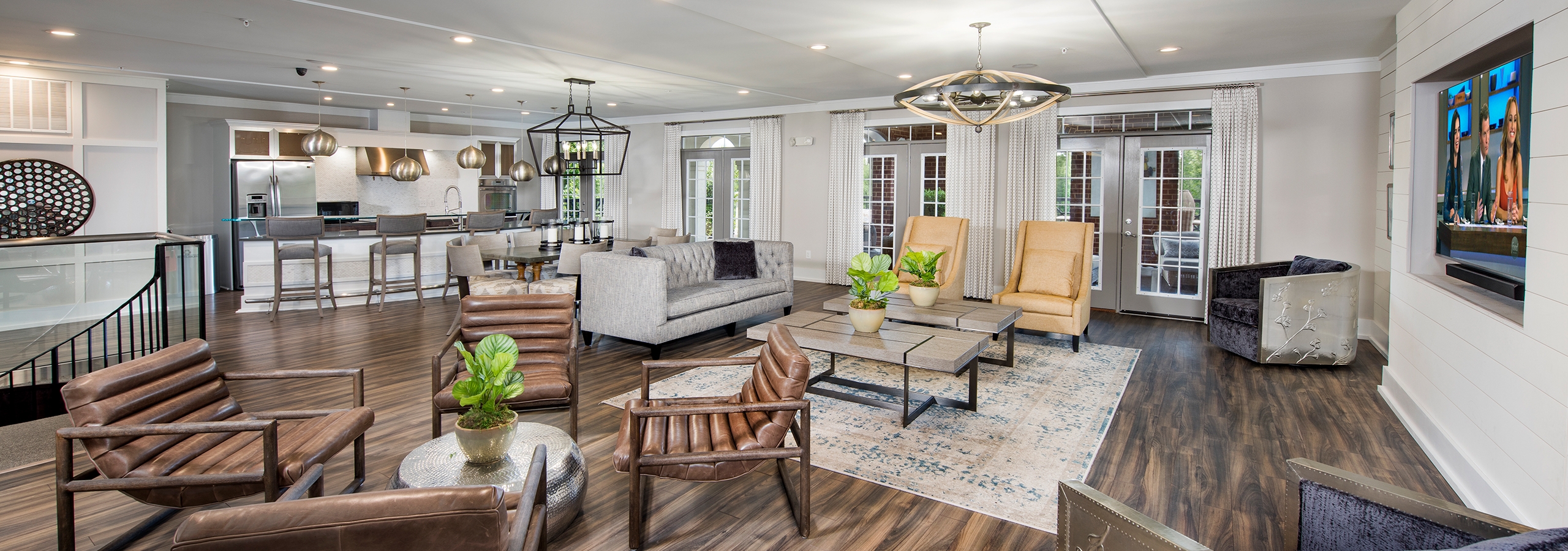 Event room at AMLI North Point with various seating options and a large TV with a barstool counter area in the background