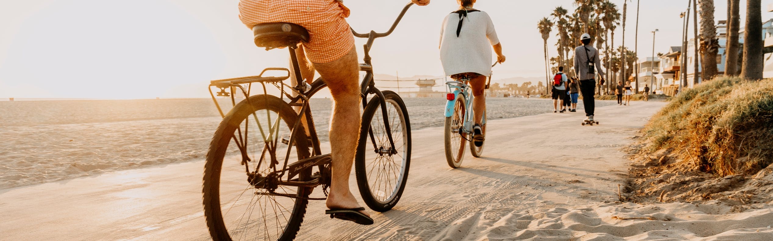 Daytime view of sandy Shoreline pedestrian bike path in Long Beach with people riding bicycles, skateboarding and walking