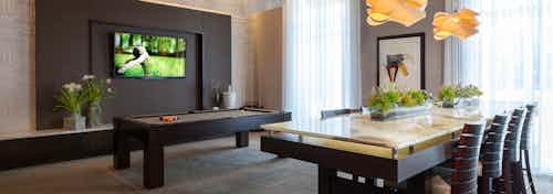 AMLI River Oaks resident lounge with billiards table, big screen TV on dark brown wall and long table with eight chairs