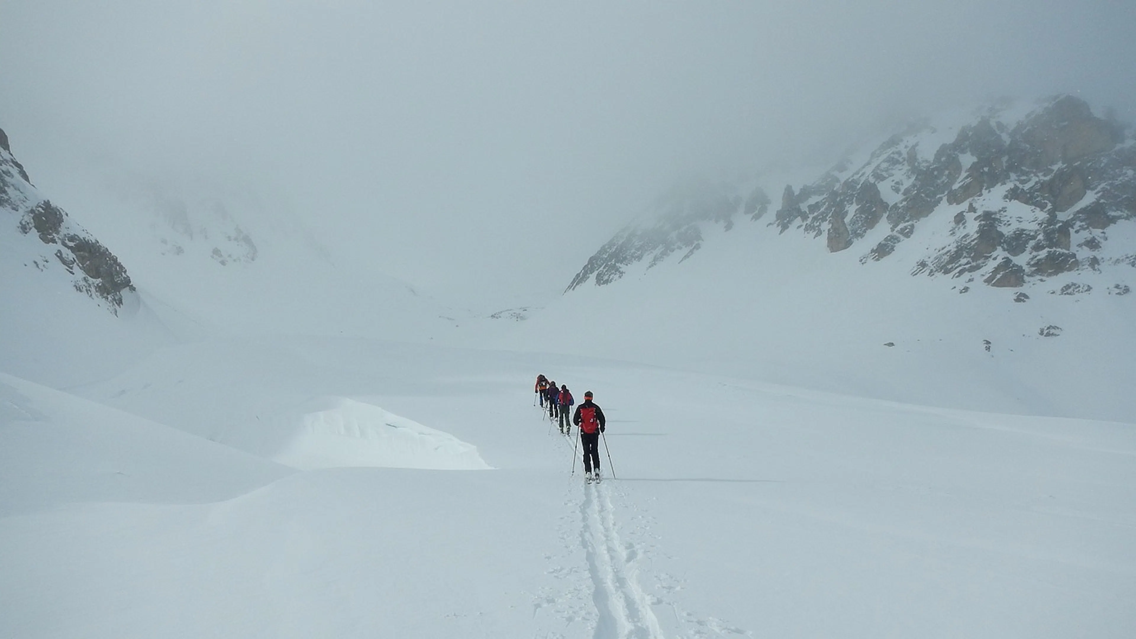 A line of cross country skiers slowly working their way through a snow covered valley
