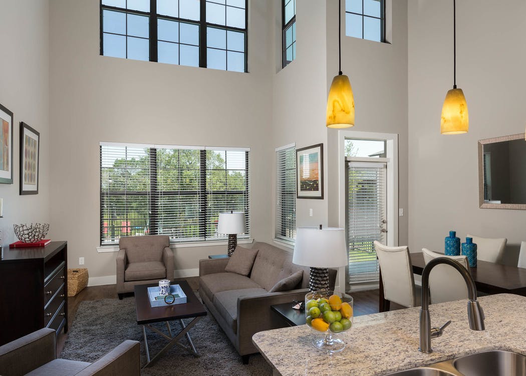 Interior of AMLI Covered Bridge living room and dining room with large windows with blinds, light walls and dark plank flooring