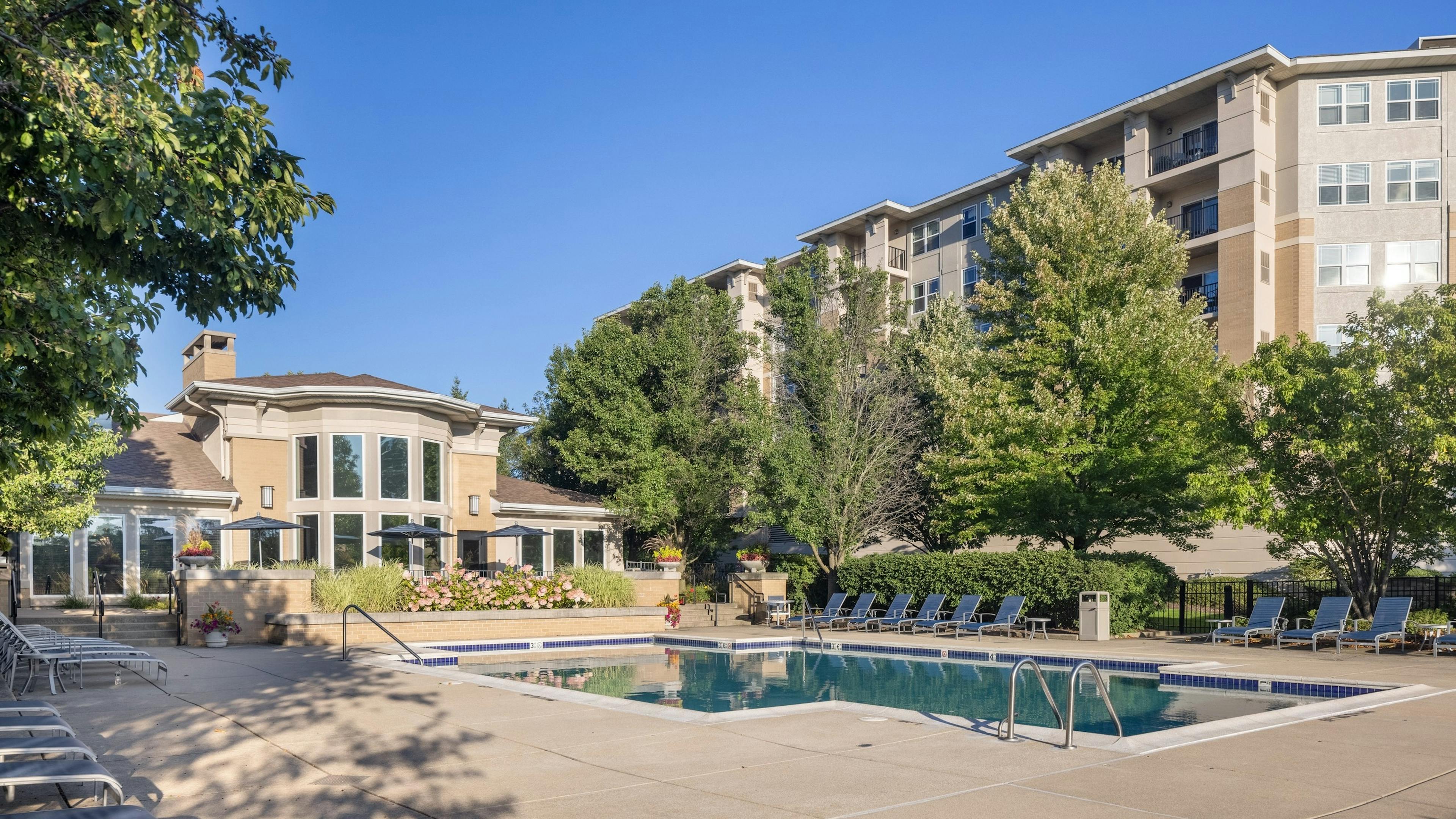 Exterior of the AMLI at Seven Bridges apartment building with behind a luxurious pool with blue lounge chairs and umbrellas