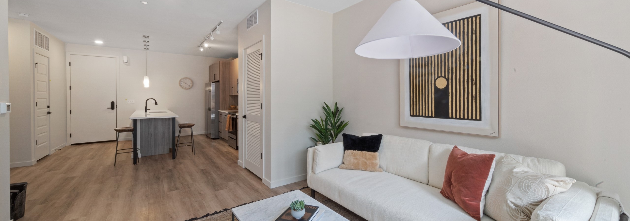 Interior view of a living room at AMLI Broadway Park with a white couch and coffee table on area rug with view into kitchen