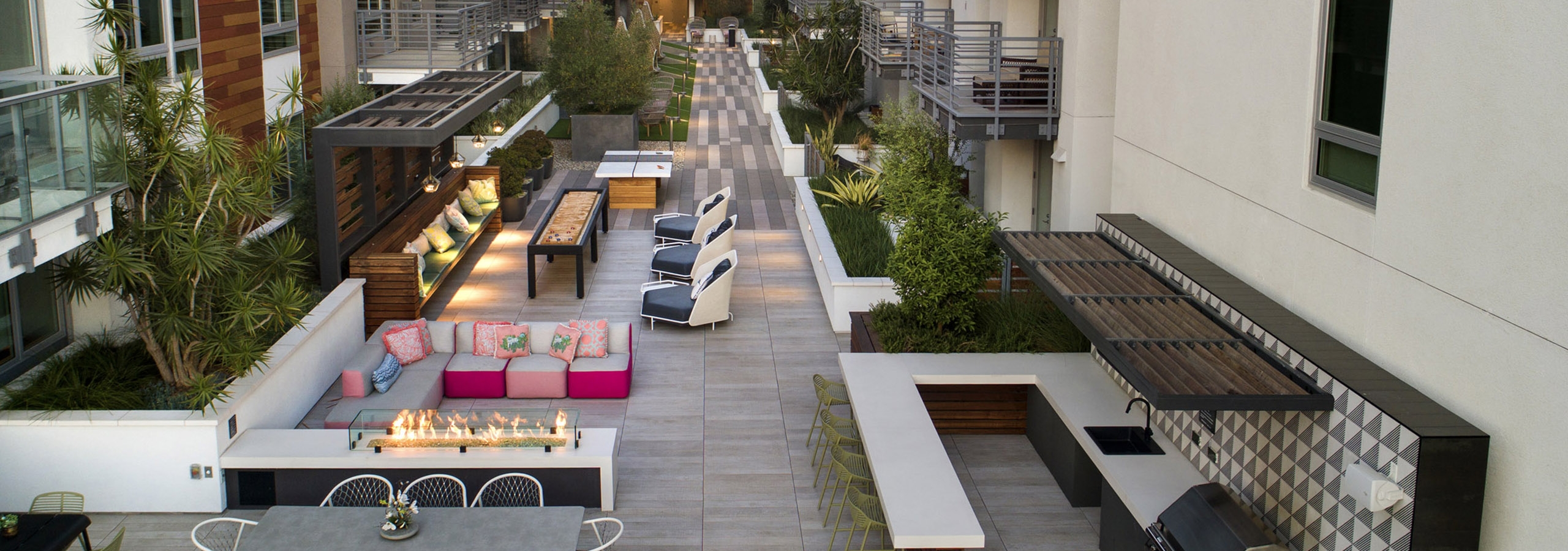 Aerial dusk view of gaming courtyard at AMLI Park Broadway with plentiful seating and grilling station and fire pit