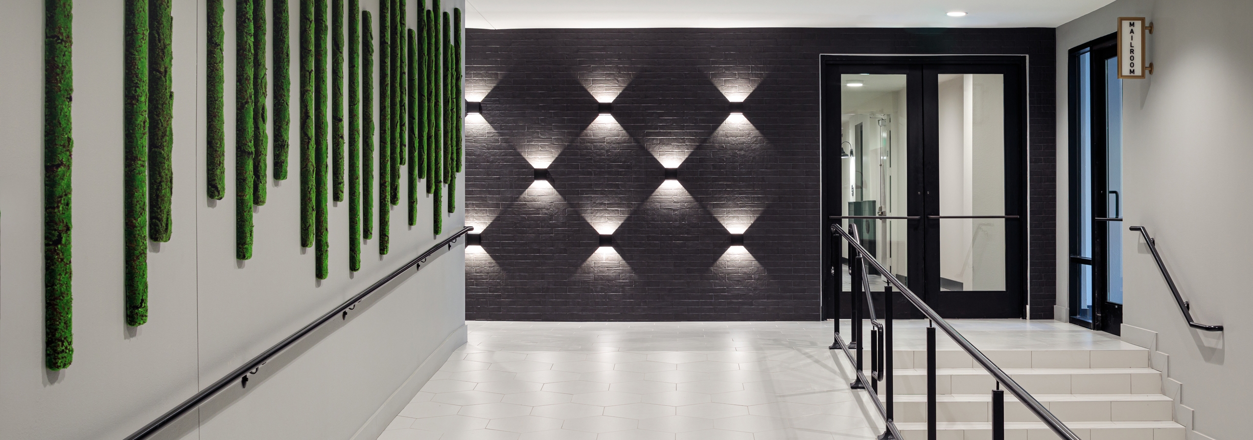 AMLI Addison hallway with green art on one wall and unique light fixtures on another wall next to staircase leading to doors
