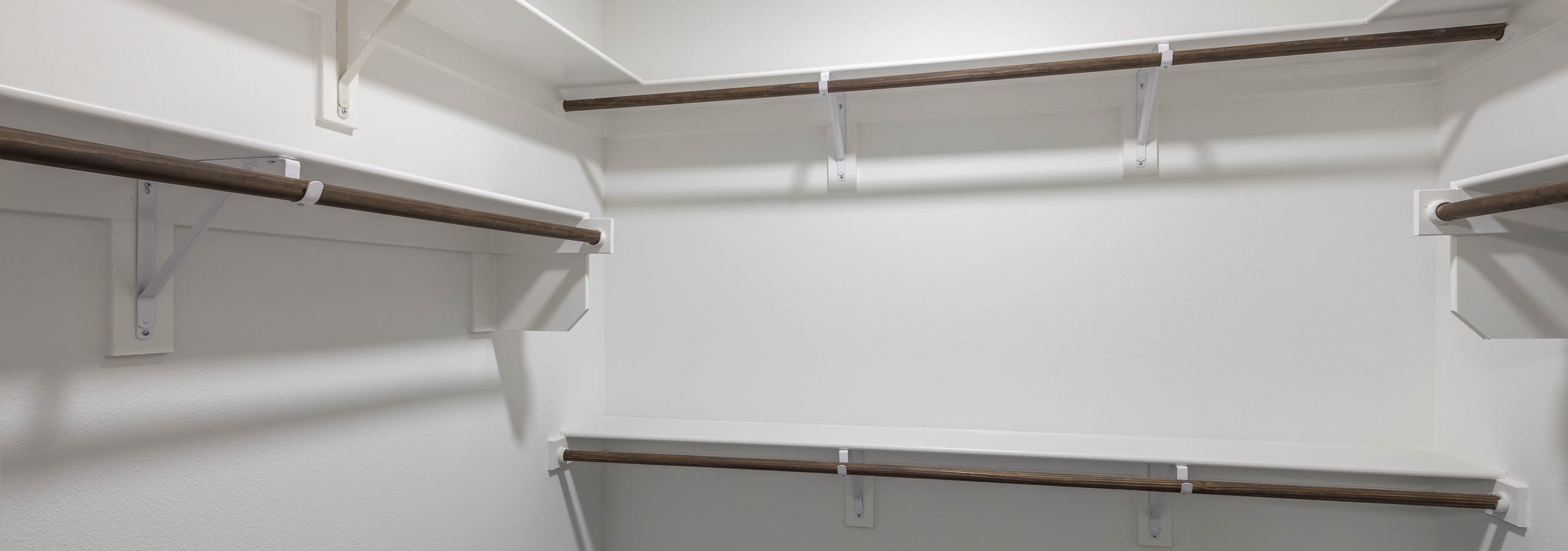 Interior view of AMLI Branch Park spacious apartment walk in closet with varying heights of built in shelving and dark floors