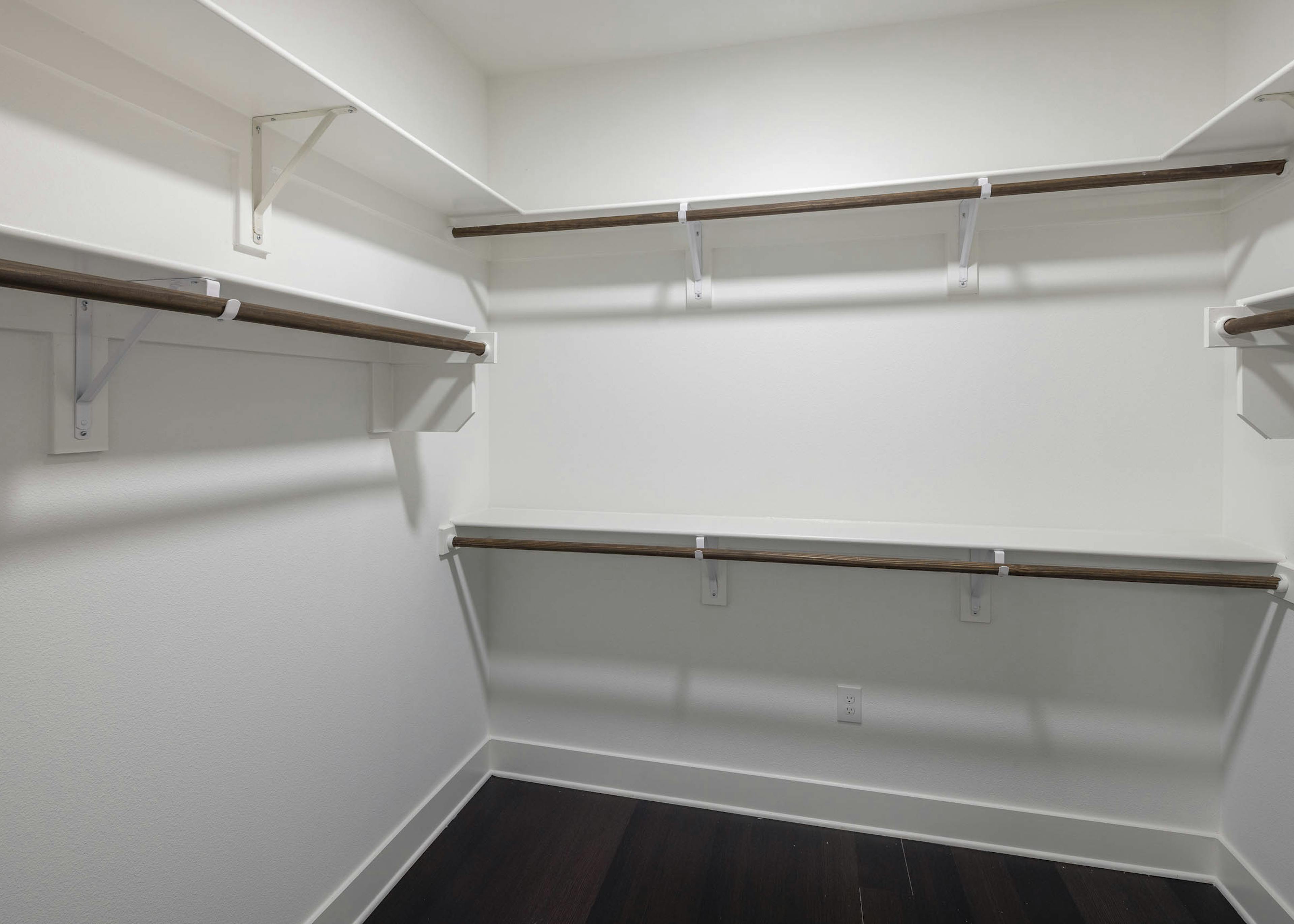 Interior view of AMLI Branch Park spacious apartment walk in closet with varying heights of built in shelving and dark floors