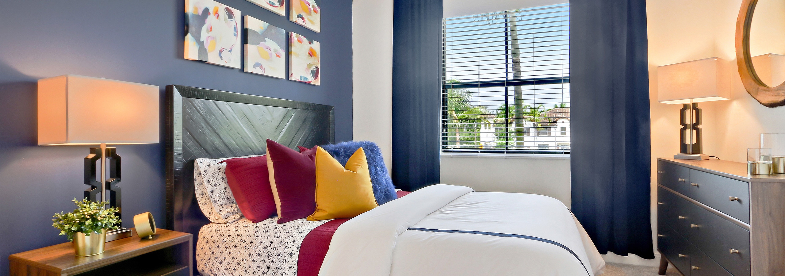 Interior view of AMLI Toscana Place townhome bedroom with bed centered on wall with décor and view from a window