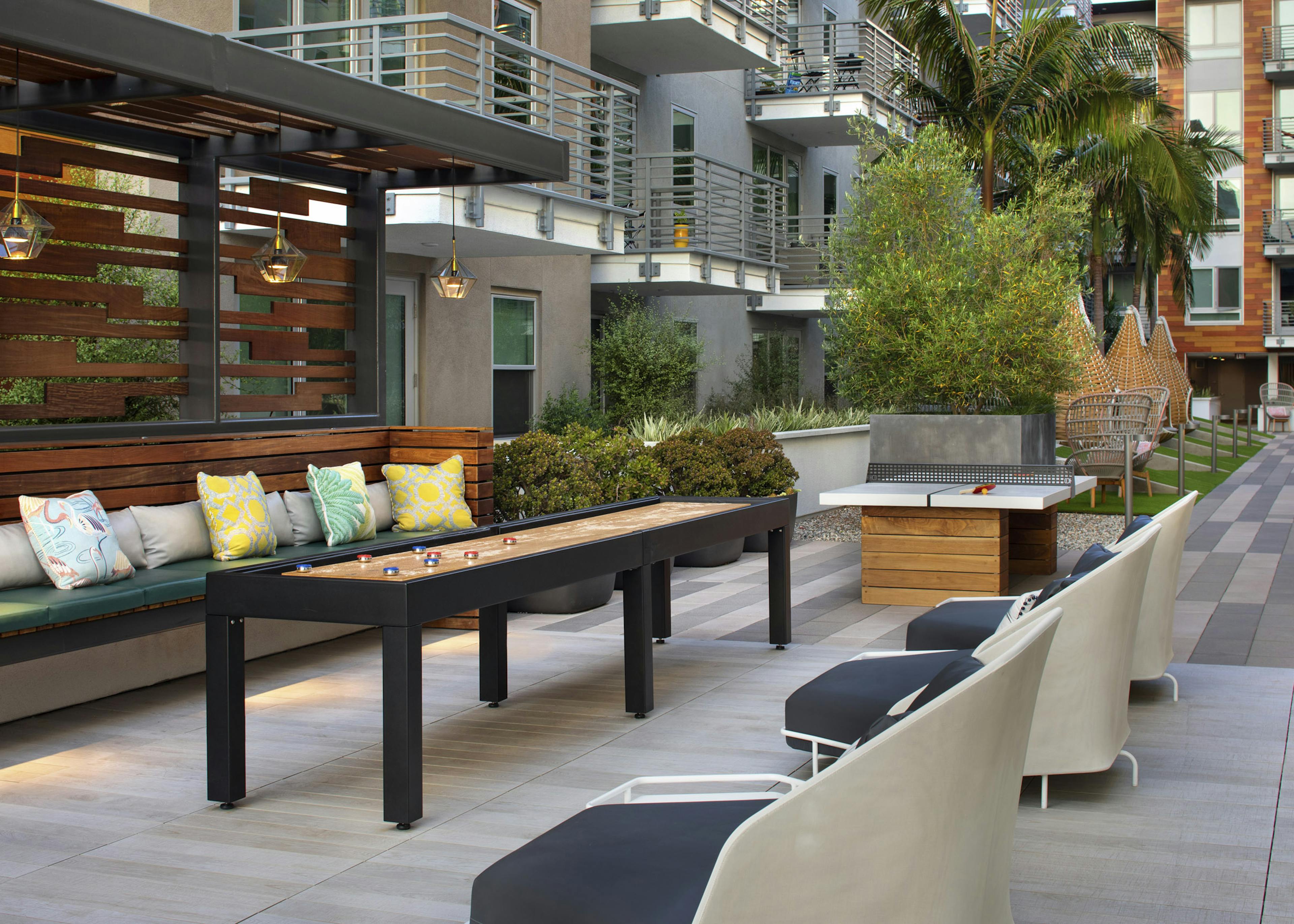 AMLI Park Broadway landscaped gaming courtyard with shuffleboard and ping pong table and seating with colorful pillows