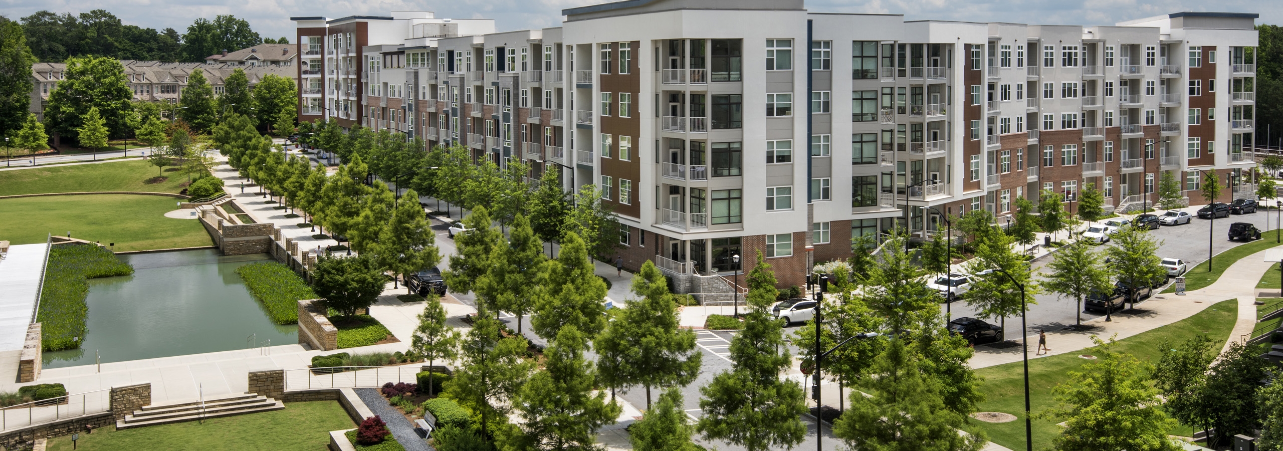 Overhead view of AMLI Buckhead apartment building and adjacent Marie Sims Park with tree lined street on a sunny day