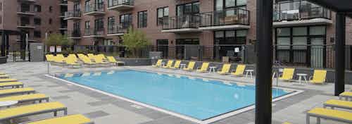 Exterior view of the swimming pool at AMLI Lofts apartment community facing the building facade in the daytime light