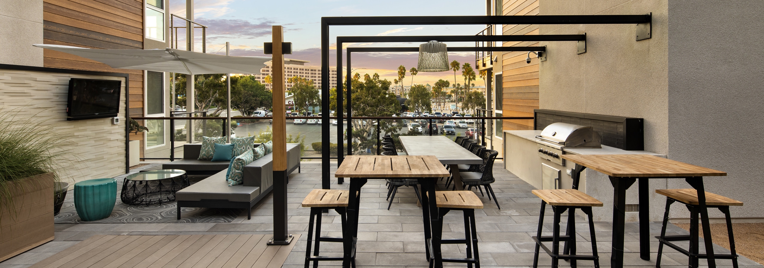 Daytime view of lounge deck overlooking Mother’s Beach with tables, grill station and big screen TV at AMLI Marina Del Rey