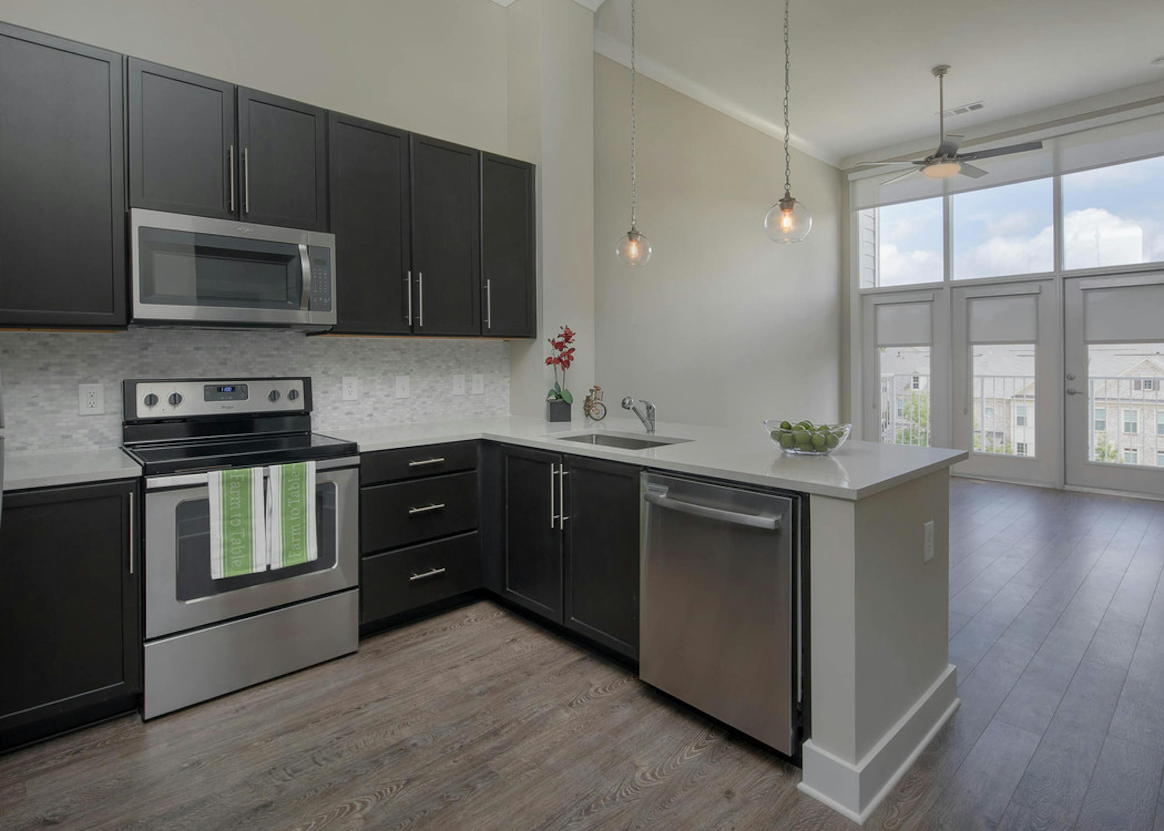 AMLI Buckhead kitchen with black cabinets and white countertops with modern light fixtures and stainless steel appliances