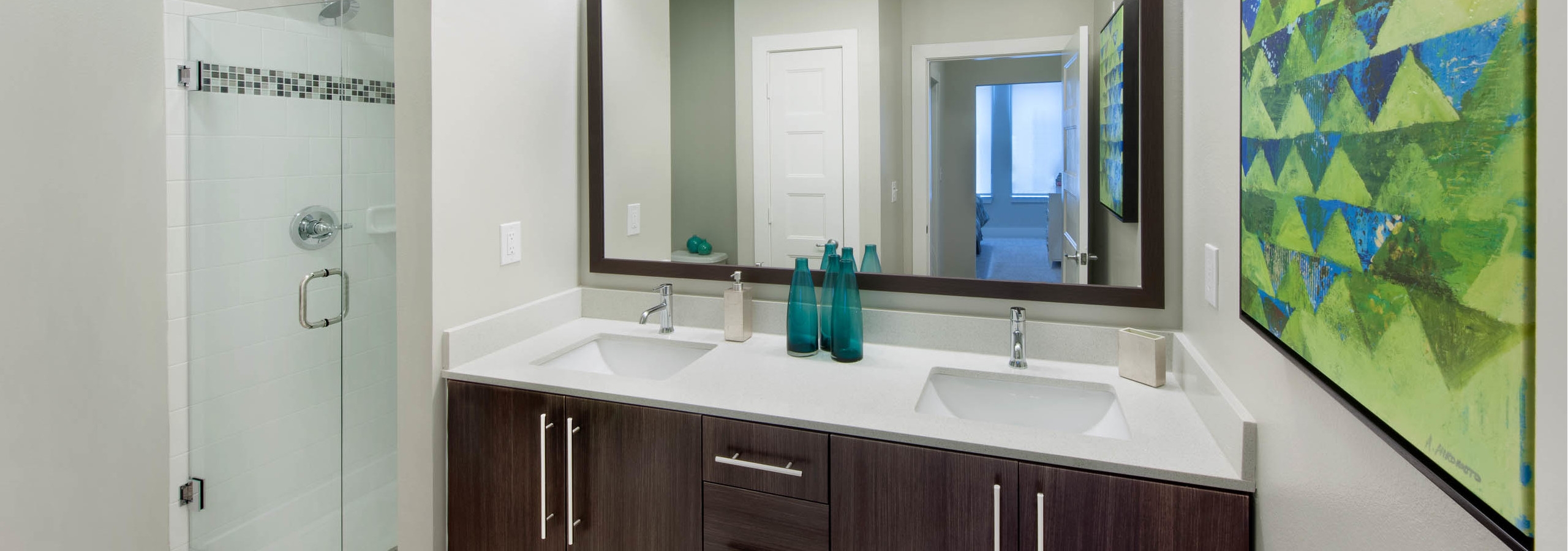 Interior view of AMLI Piedmont Heights apartment bathroom with double dark wood vanity sink with a mirror and stand up shower