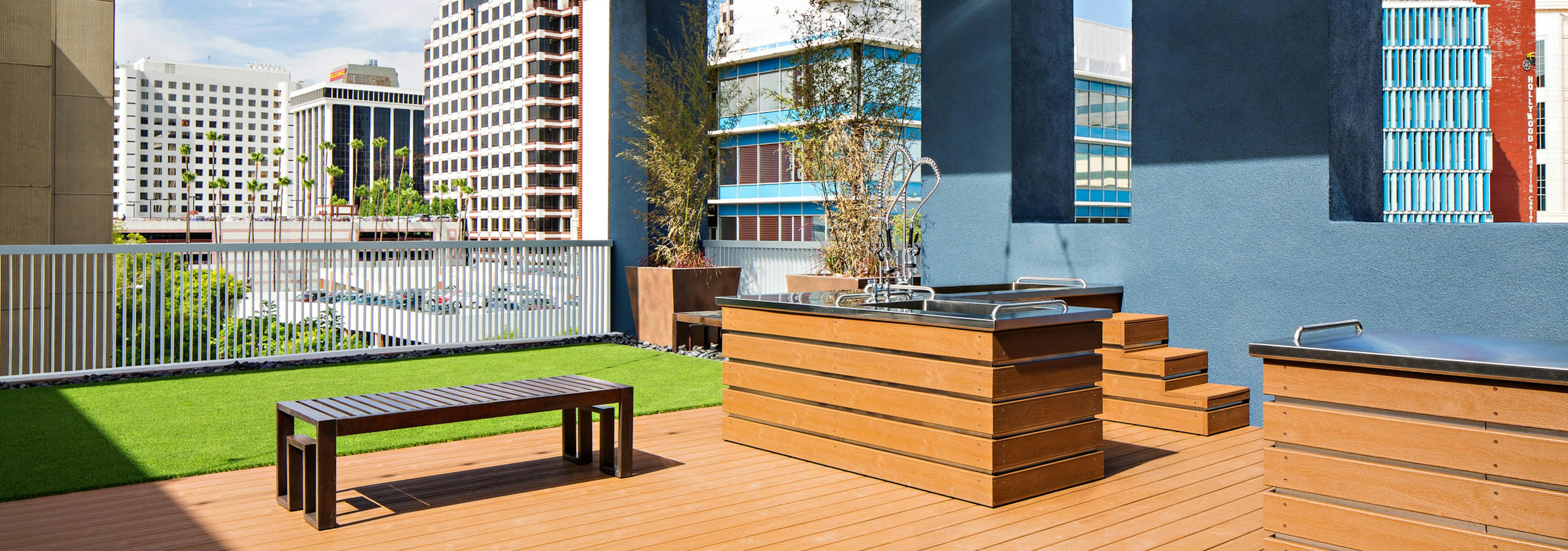 Daytime view of Rooftop pet park with dog spa overlooking the city at AMLI Lex on Orange apartments with turf rug and bench