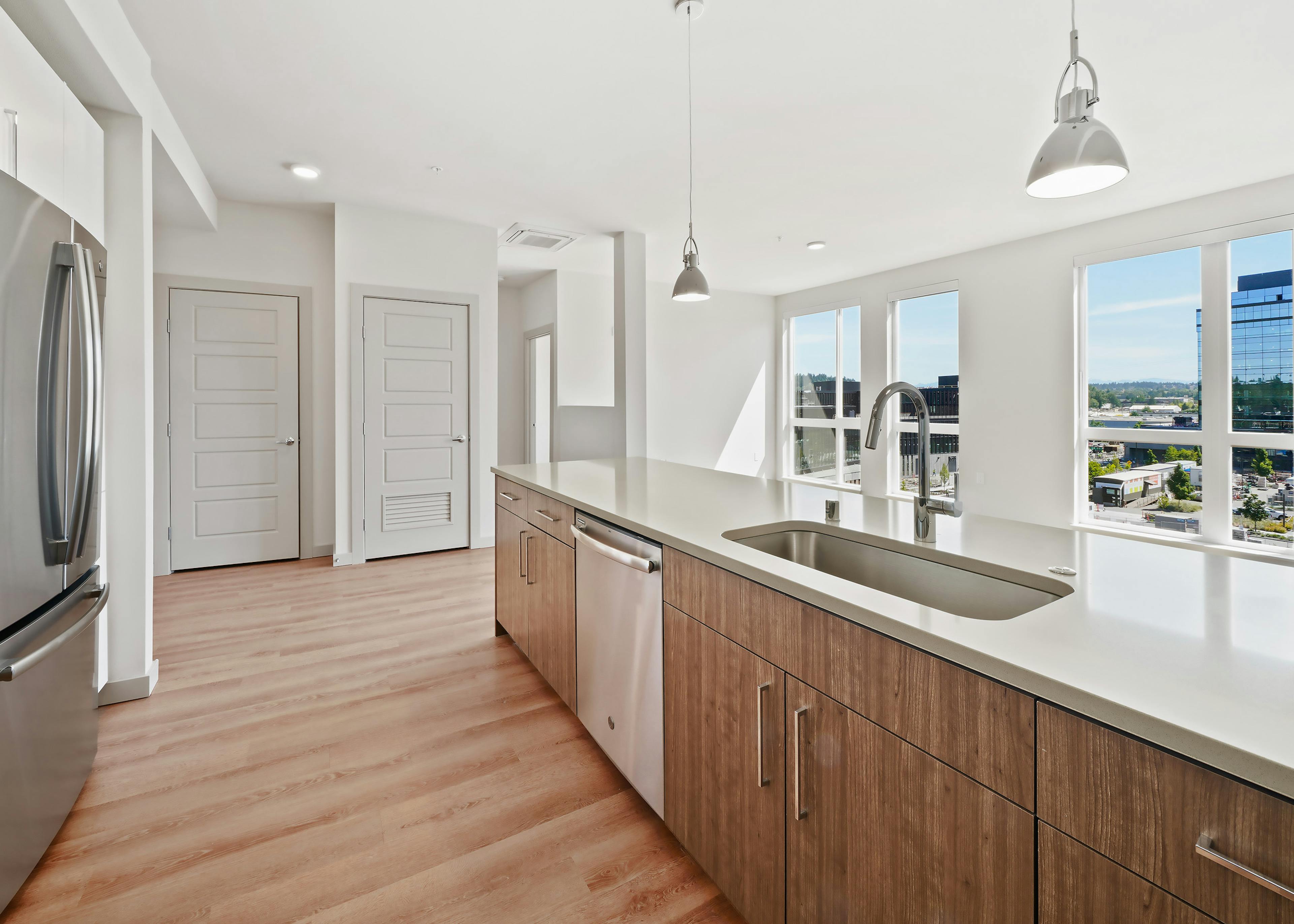 Long kitchen Island with white quartz countertops and wood cabinets and stainless appliances at AMLI Spring District