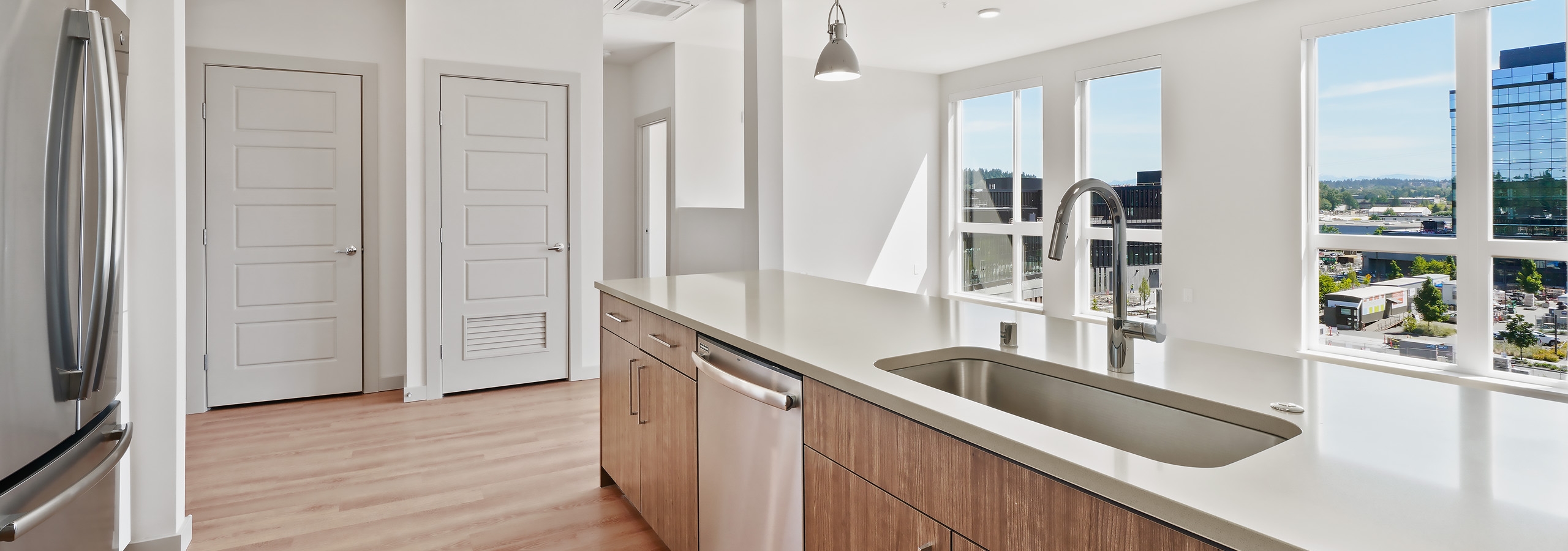 Long kitchen Island with white quartz countertops and wood cabinets and stainless appliances at AMLI Spring District