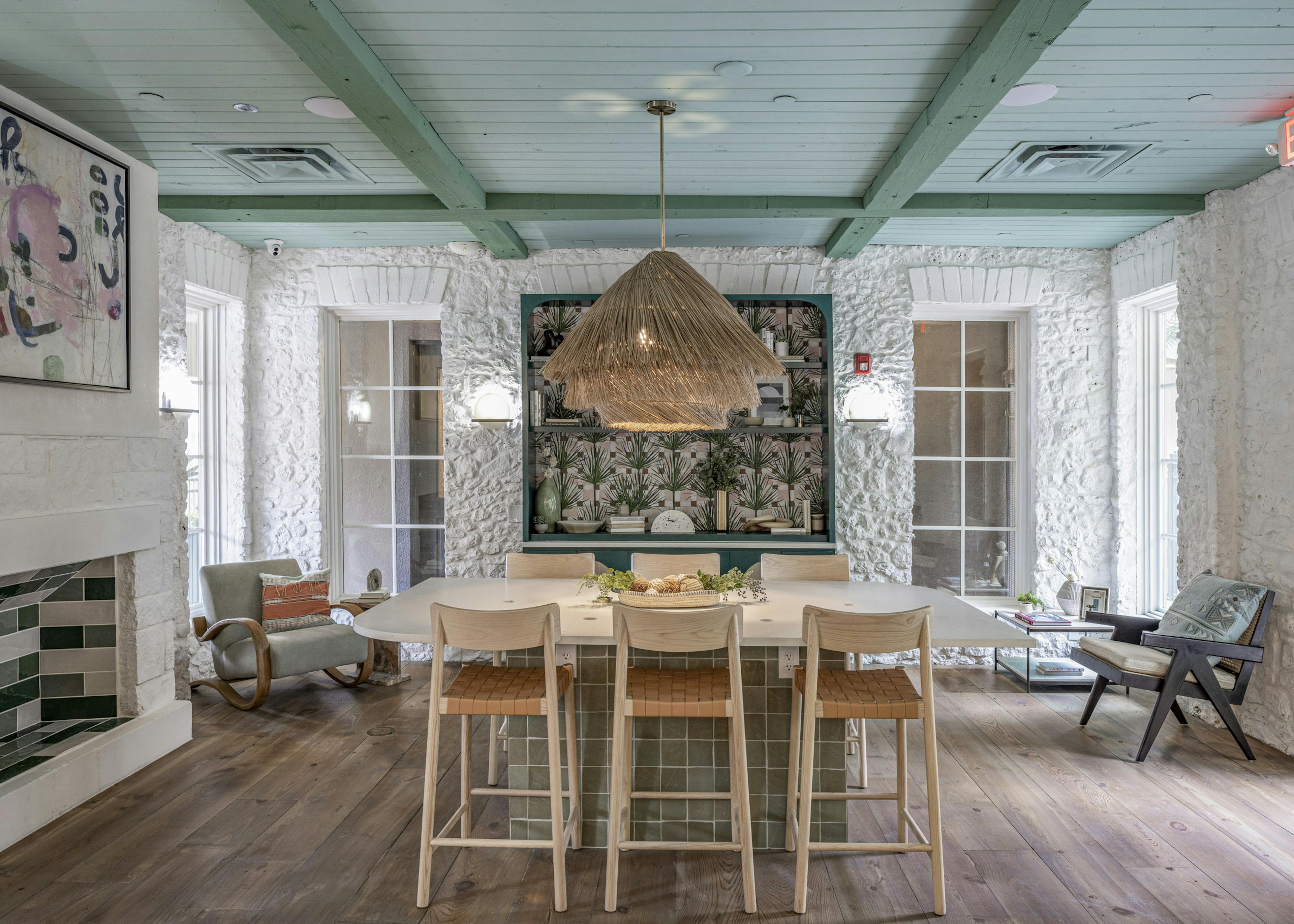 Interior view of AMLI 300 resident lounge with white table with 6 wooden chairs and white stone walls and green beamed ceiling 