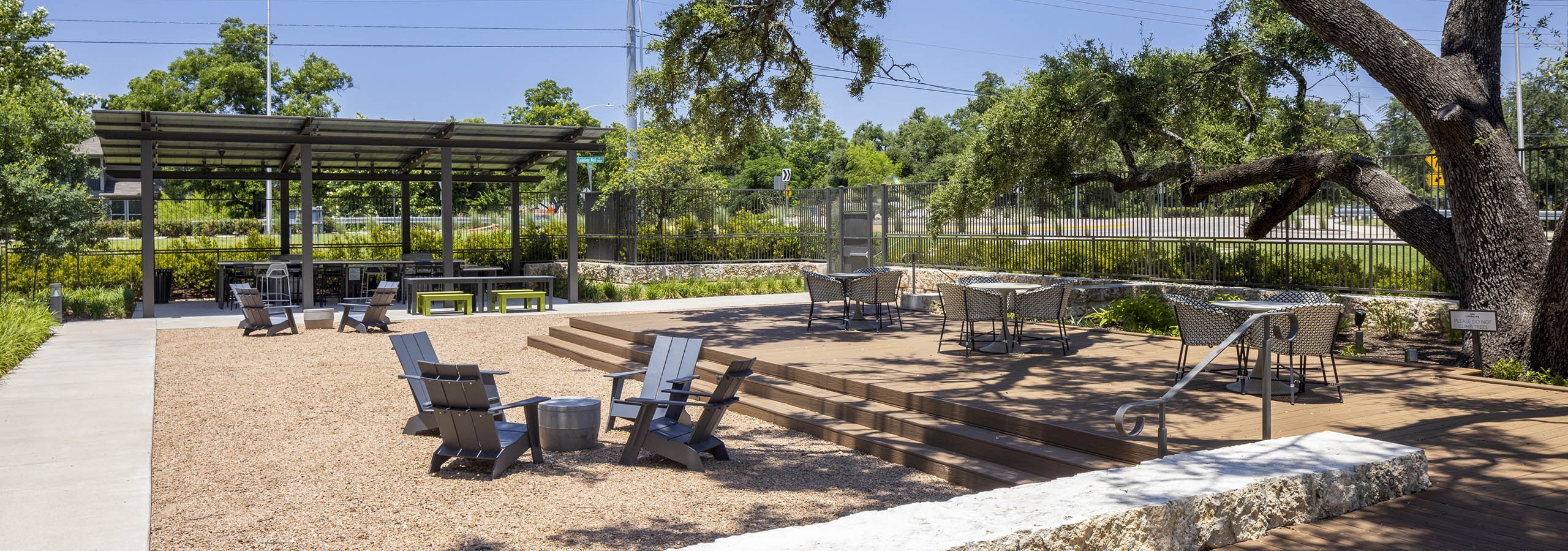 Social terrace at AMLI Lakeline with a wood deck and outdoor seating with lush greenery next to covered entertainment area
