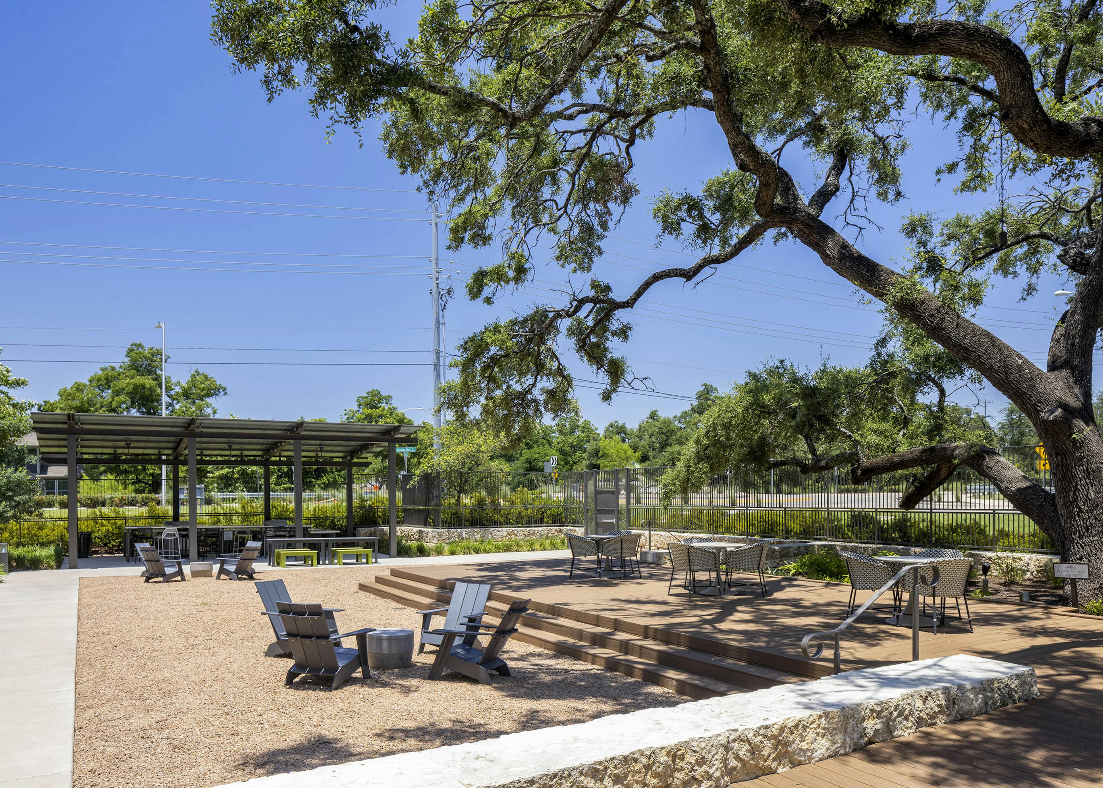 Social terrace at AMLI Lakeline with a wood deck and outdoor seating with lush greenery next to covered entertainment area