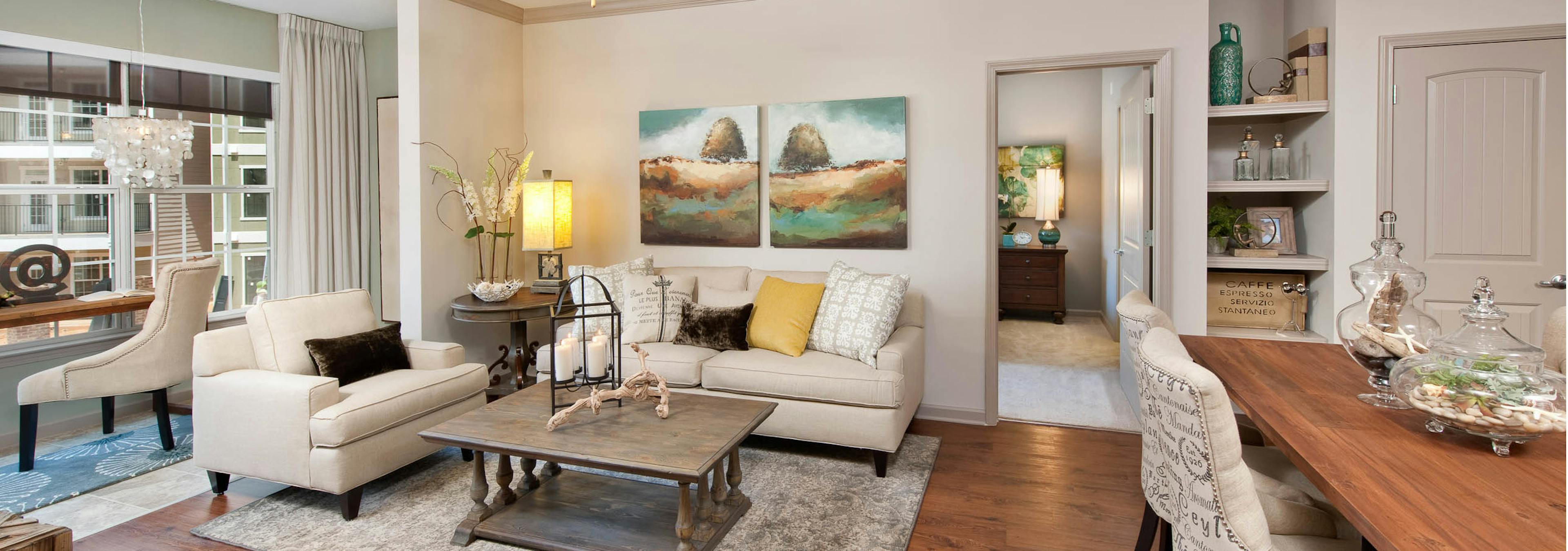 Living room at AMLI North Point with a large window and chestnut colored wood floors with neutral, elegant decor