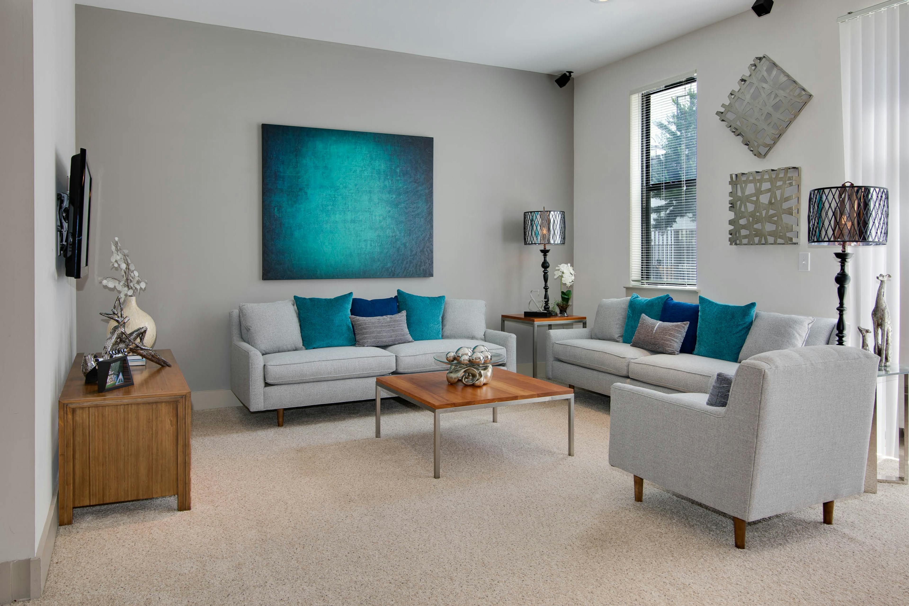 AMLI Old 4th Ward living room with grey seating and neutral carpet flooring leading to kitchen in the background