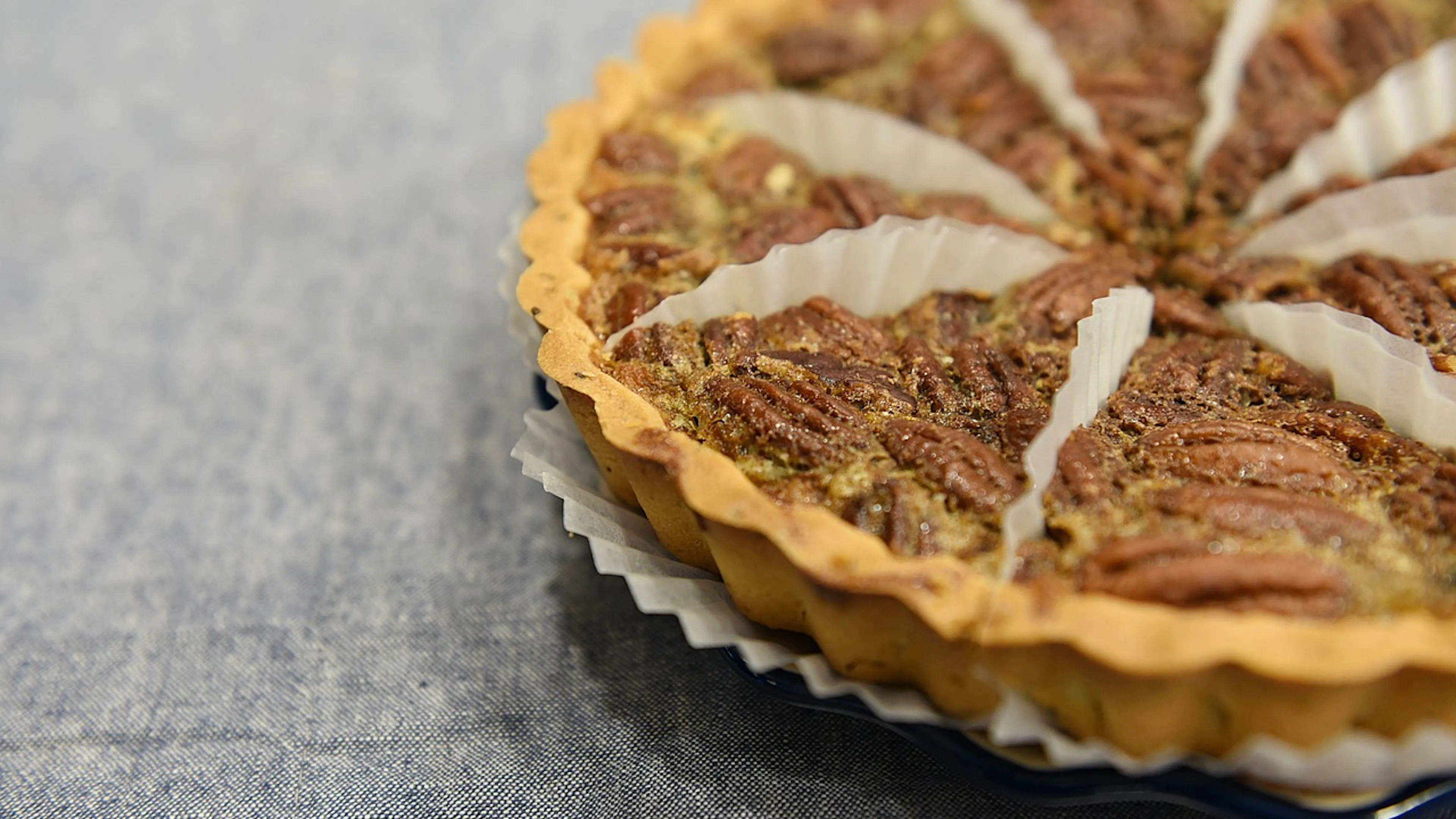 A closeup of a pecan pie cut into slices with parchment paper in between