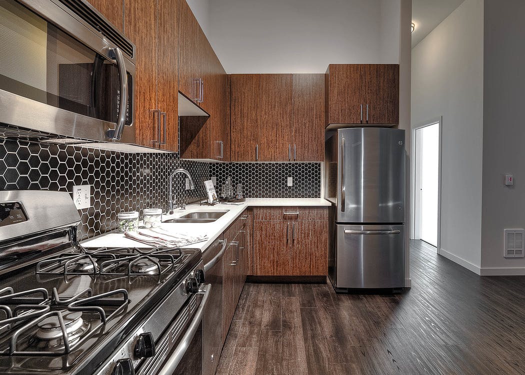 Apartment kitchen at AMLI South Lake Union with dark cabinets and white quartz counters and tile back splash