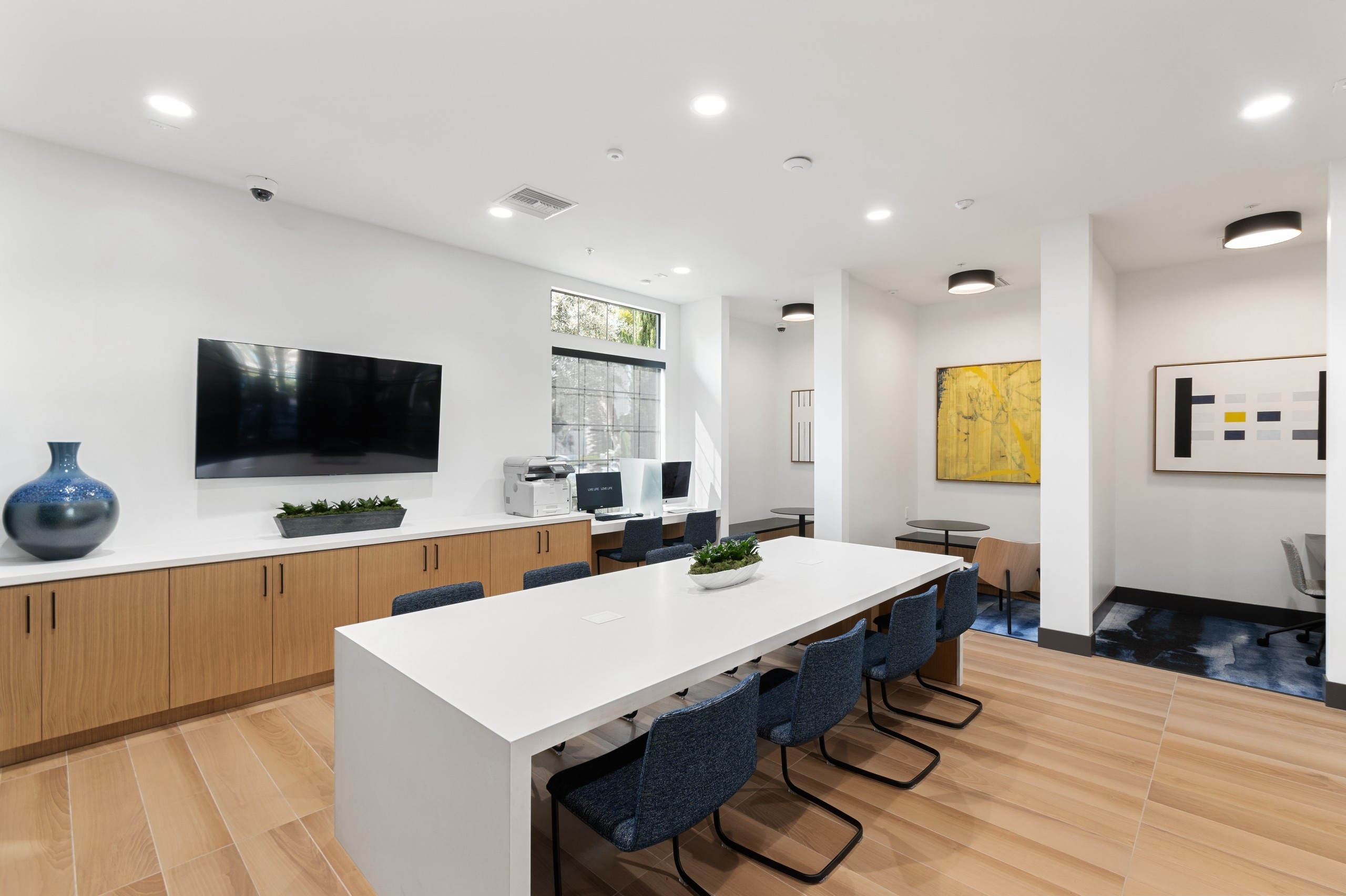 Daytime view of WiFi lounge at AMLI Spanish Hills apartments with alcove offices and big screen TV and workspaces