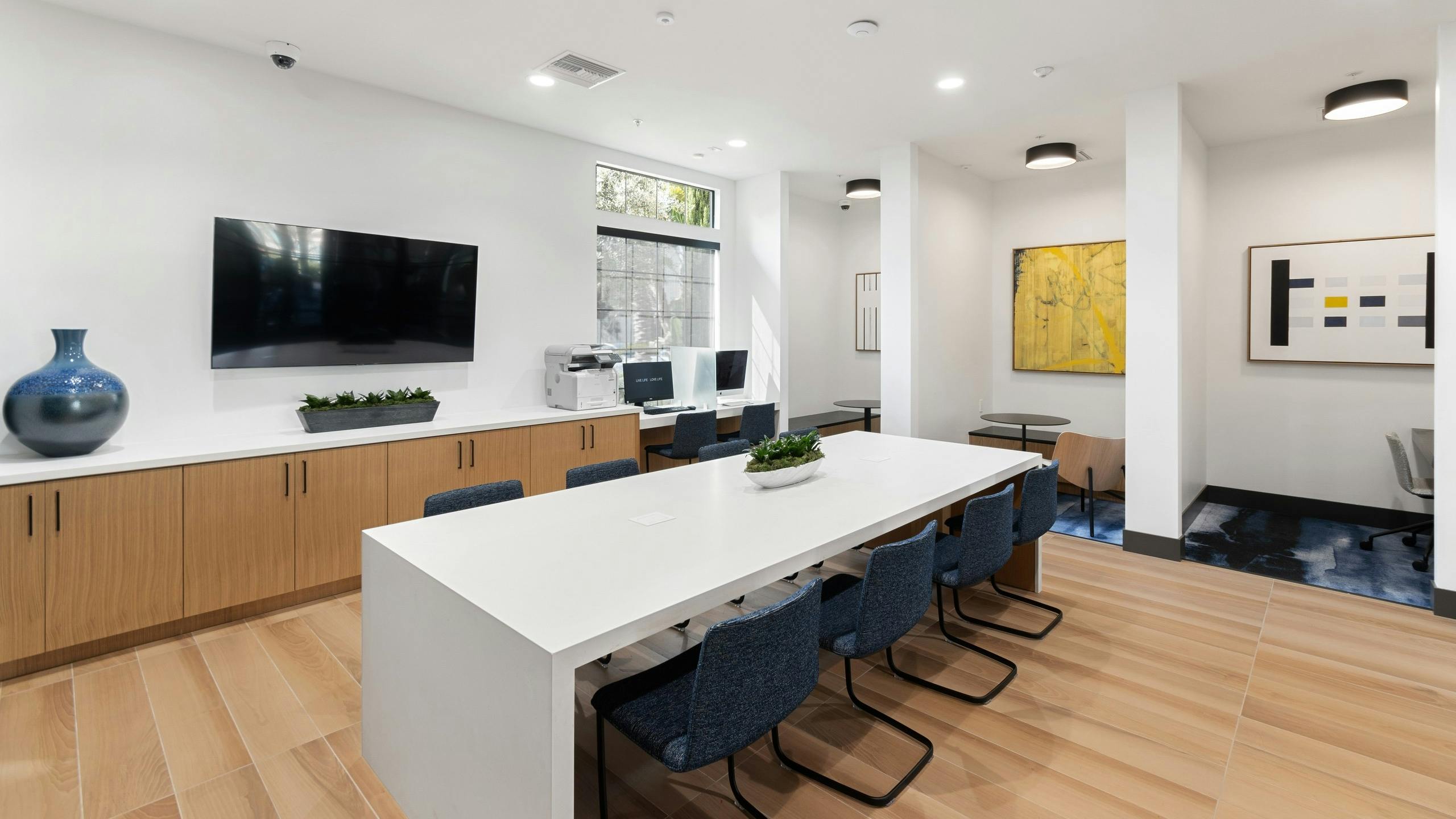 Daytime view of WiFi lounge at AMLI Spanish Hills apartments with alcove offices and big screen TV and workspaces