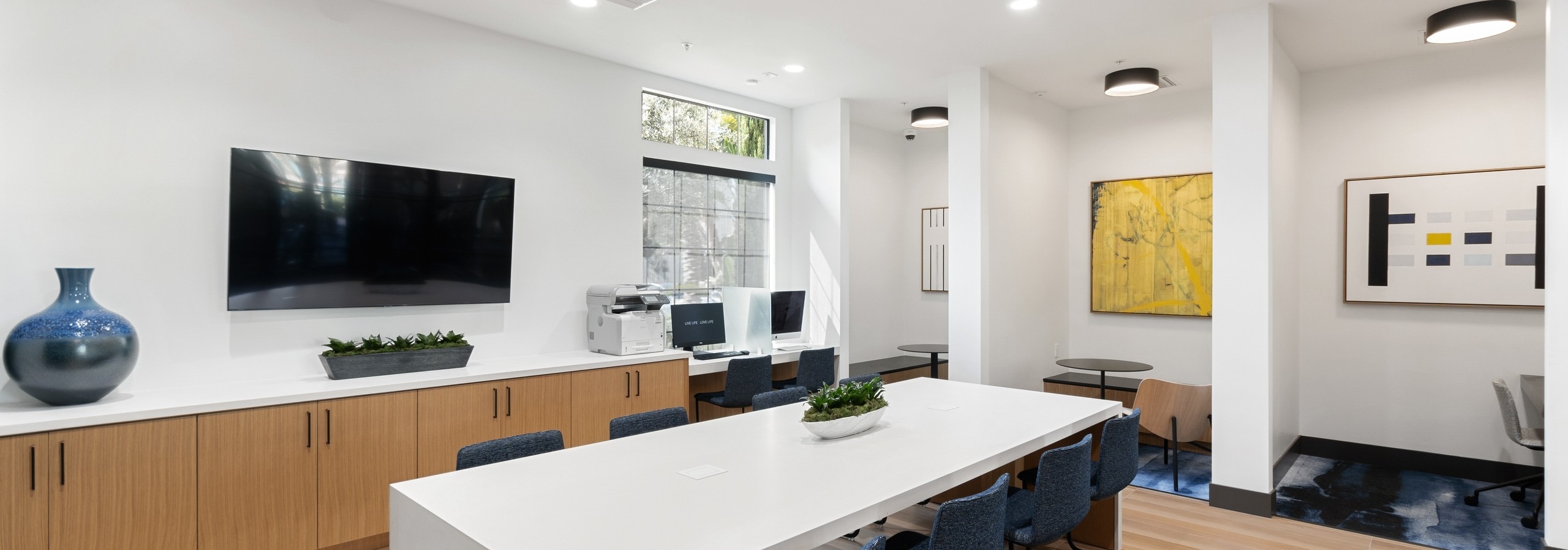 Daytime view of WiFi lounge at AMLI Spanish Hills apartments with alcove offices and big screen TV and workspaces