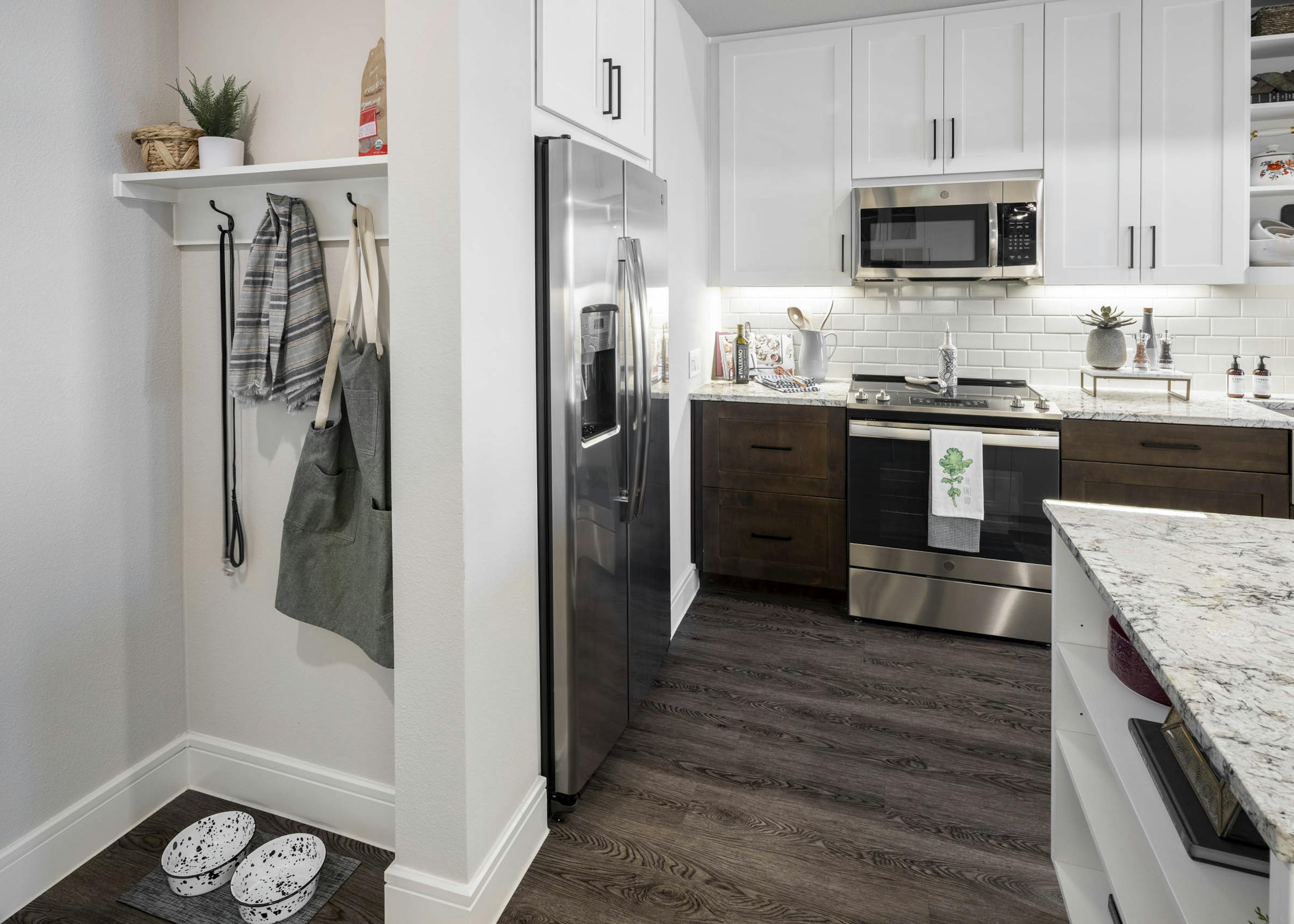 Mudroom at AMLI Lakeline apartment with storage hooks and shelf near apartment kitchen equipped with stainless steel fridge