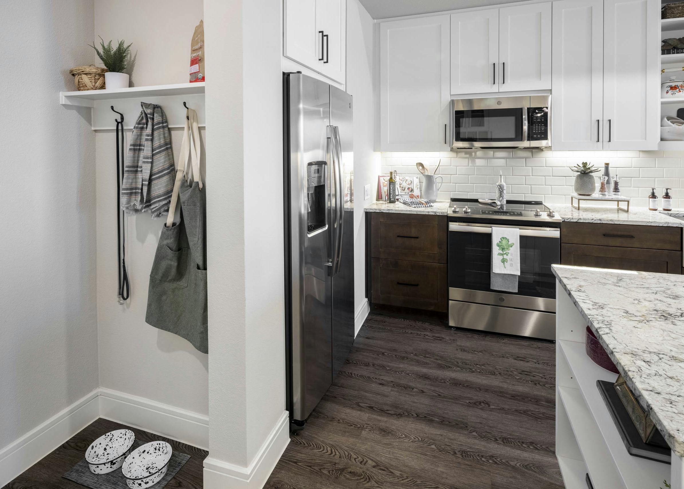 Mudroom at AMLI Lakeline apartment with storage hooks and shelf near apartment kitchen equipped with stainless steel fridge