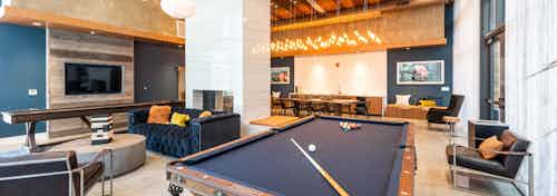 Interior of clubhouse with shuffle board, pool table and elegant blue couch and pendant light AMLI Marina Del Rey apartments