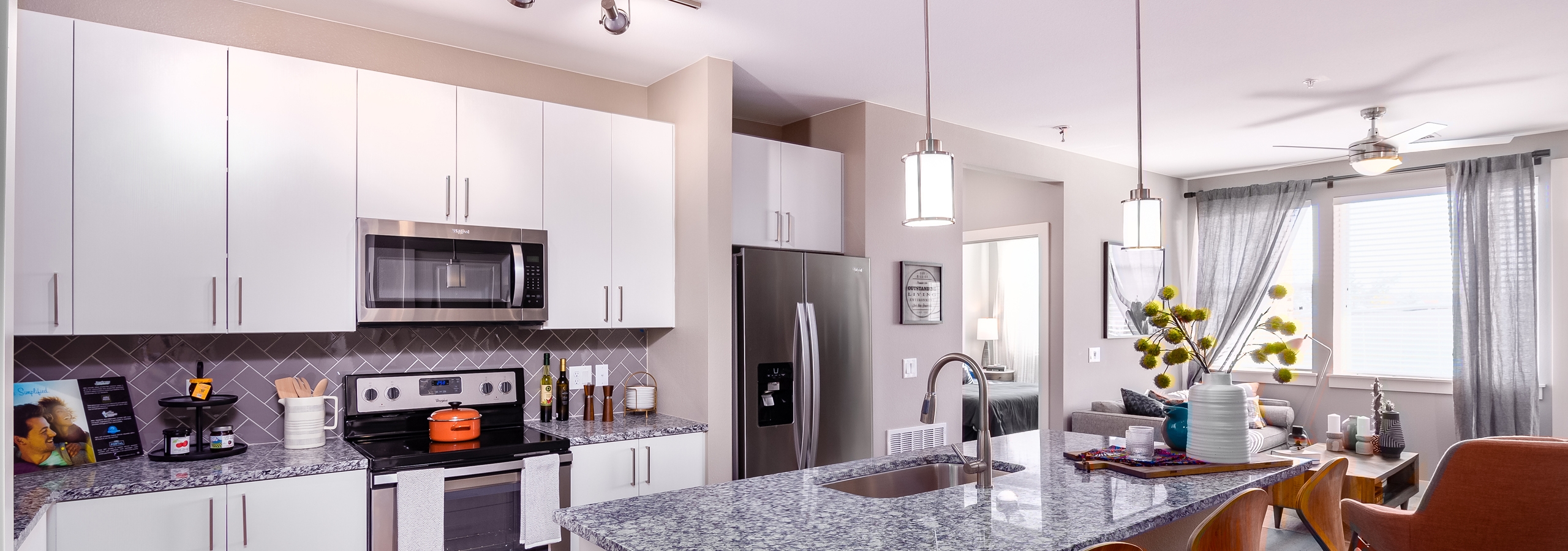 Interior of AMLI Littleton Village apartment kitchen with granite countertops, stainless steel appliances and white cabinetry