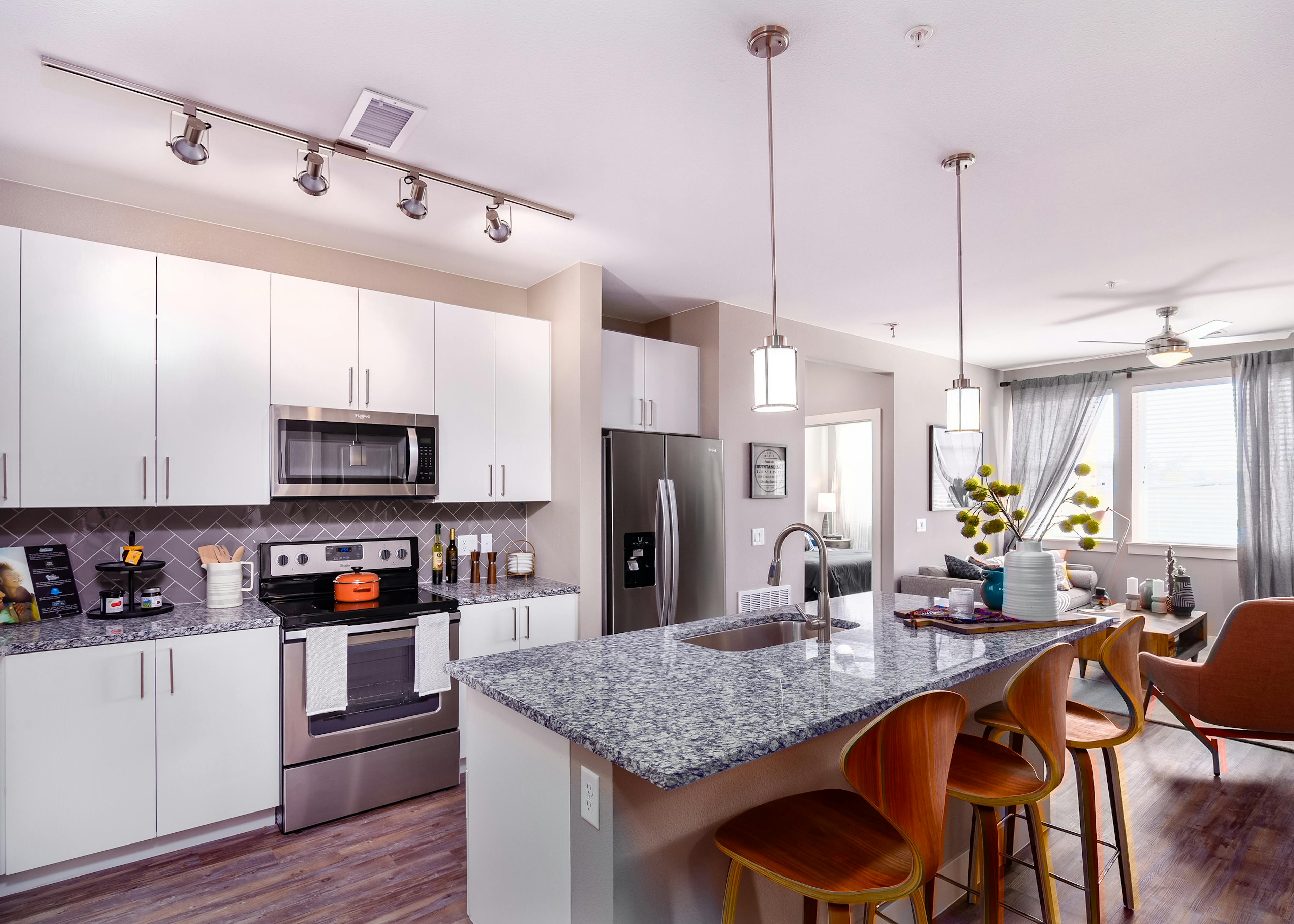 Interior of AMLI Littleton Village apartment kitchen with granite countertops, stainless steel appliances and white cabinetry