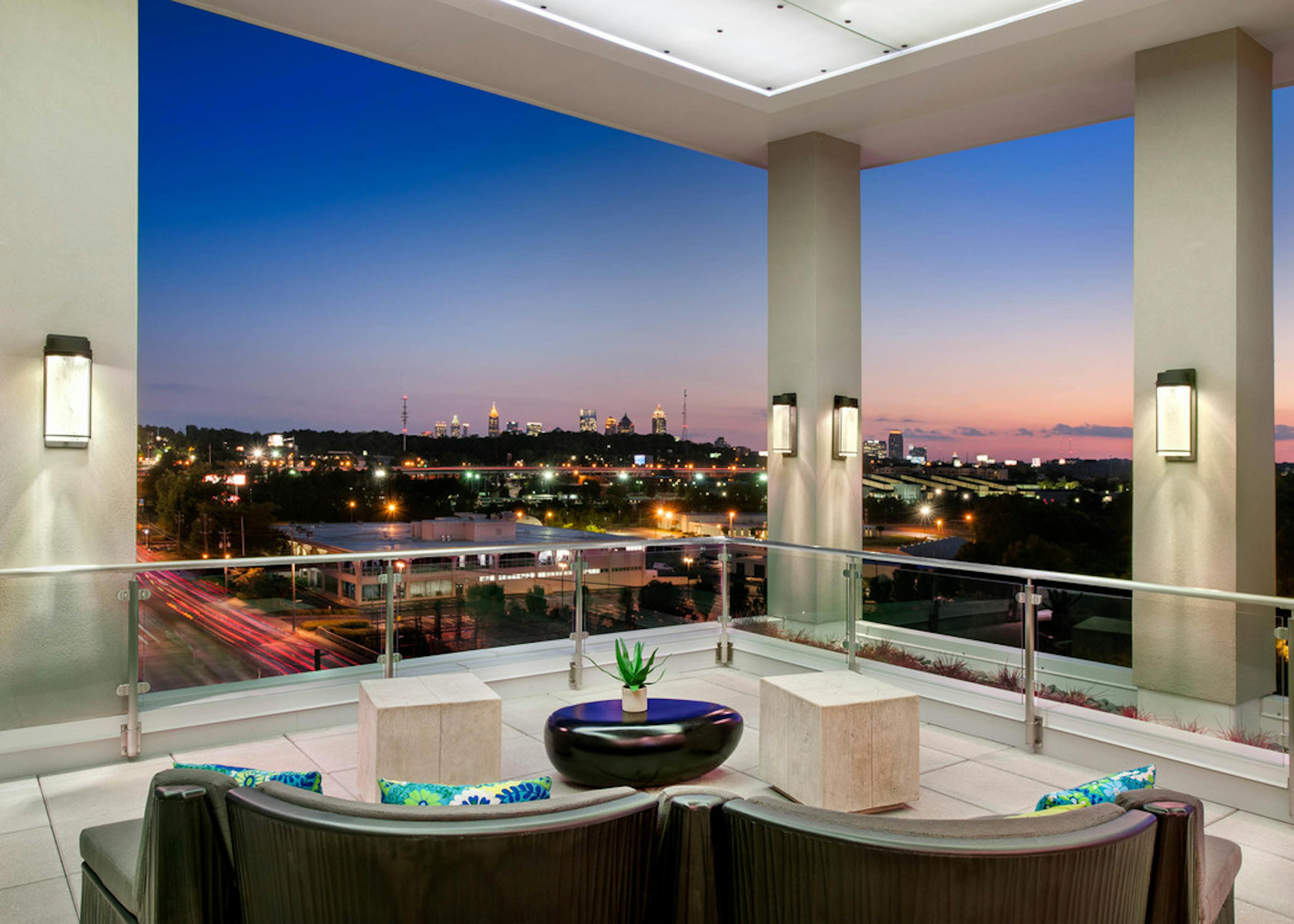 Nighttime exterior shot of AMLI Piedmont Heights sky deck with various couch seating to overlook lit up Atlanta skyline
