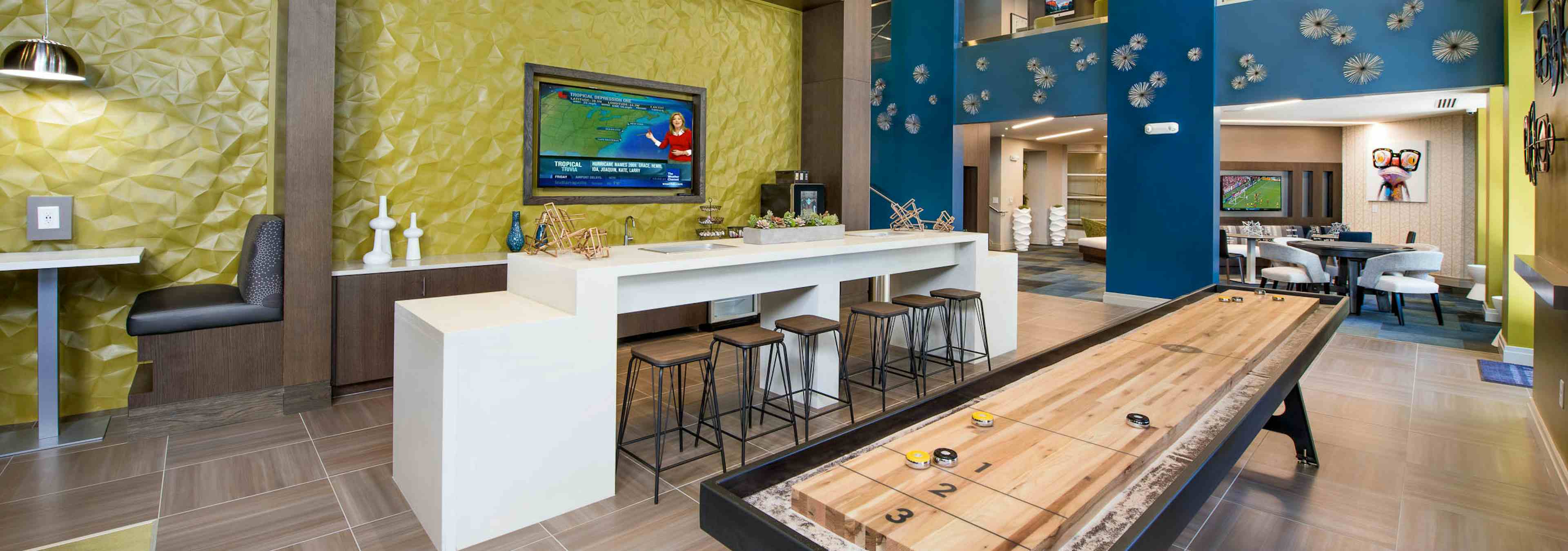 Clubroom at AMLI Buckhead with yellow and blue textured walls and booth seating with a white counter and industrial barstools