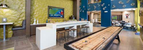 Clubroom at AMLI Buckhead with yellow and blue textured walls and booth seating with a white counter and industrial barstools