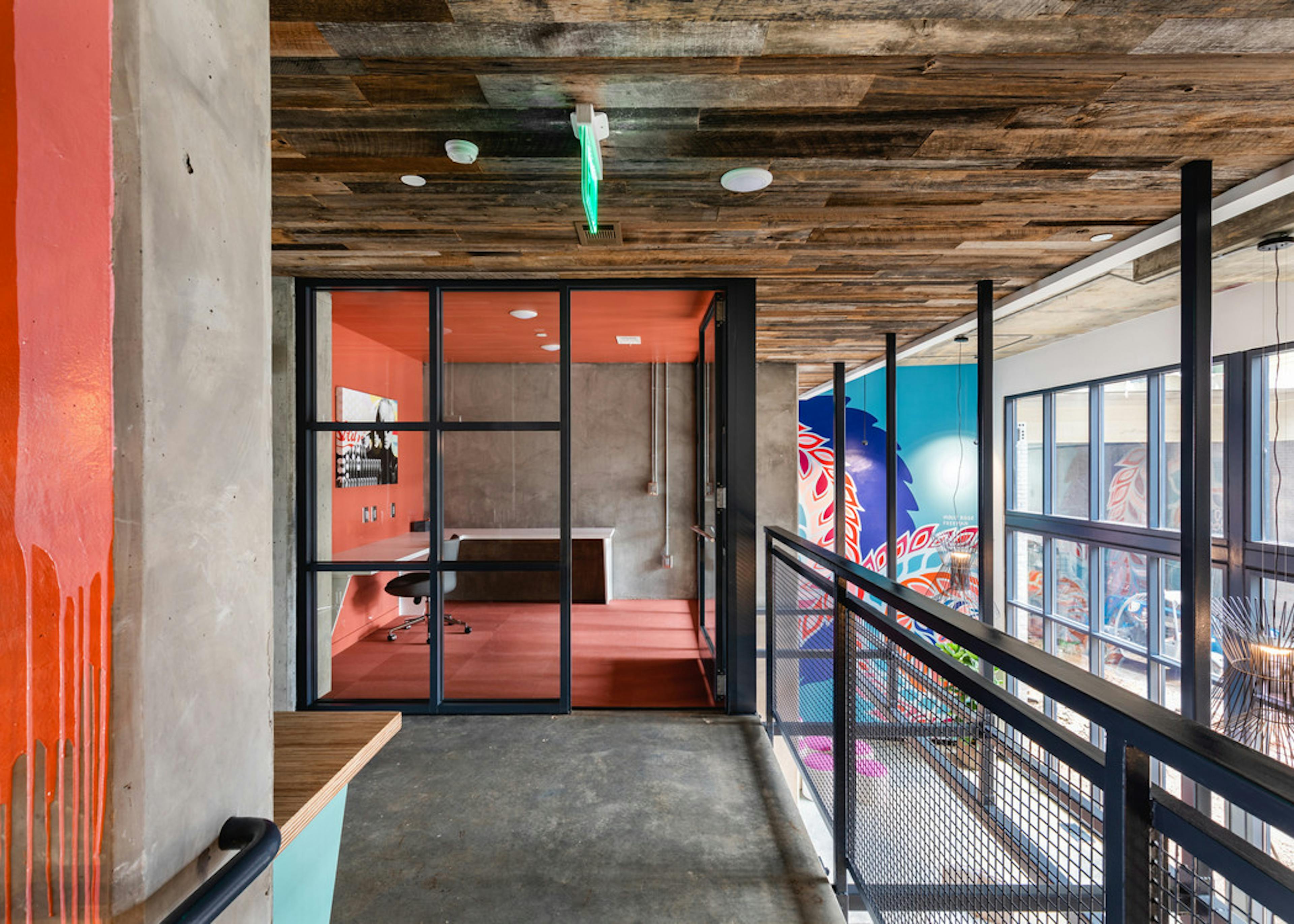 AMLI Westside community work spaces with concrete flooring and colorful private offices with glass doors and large windows