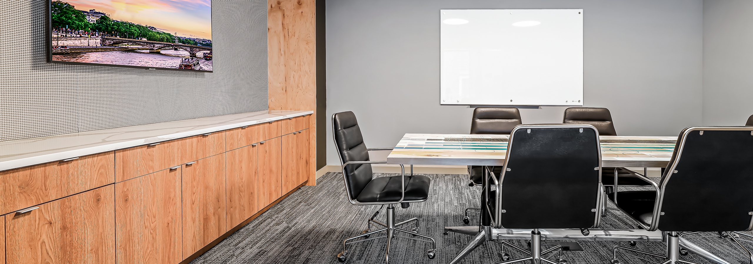 Conference room at AMLI Spring District with white table and 6 black chairs and whiteboard and mounted TV over wood cabinets