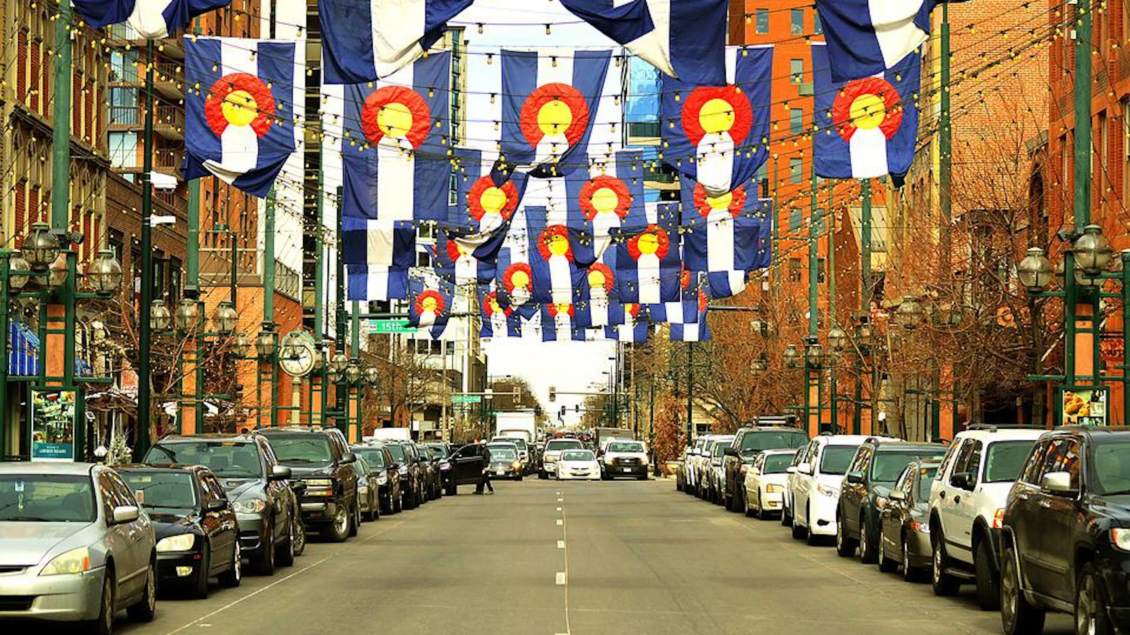 Colorado flags hanging over the road in Larimer square lined by brick buildings