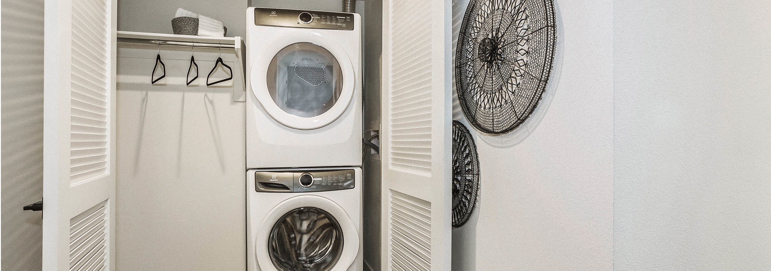 View of full sized front loading stacked washer and dryer closet with laundry hanging rod at AMLI Marina Del Rey apartments