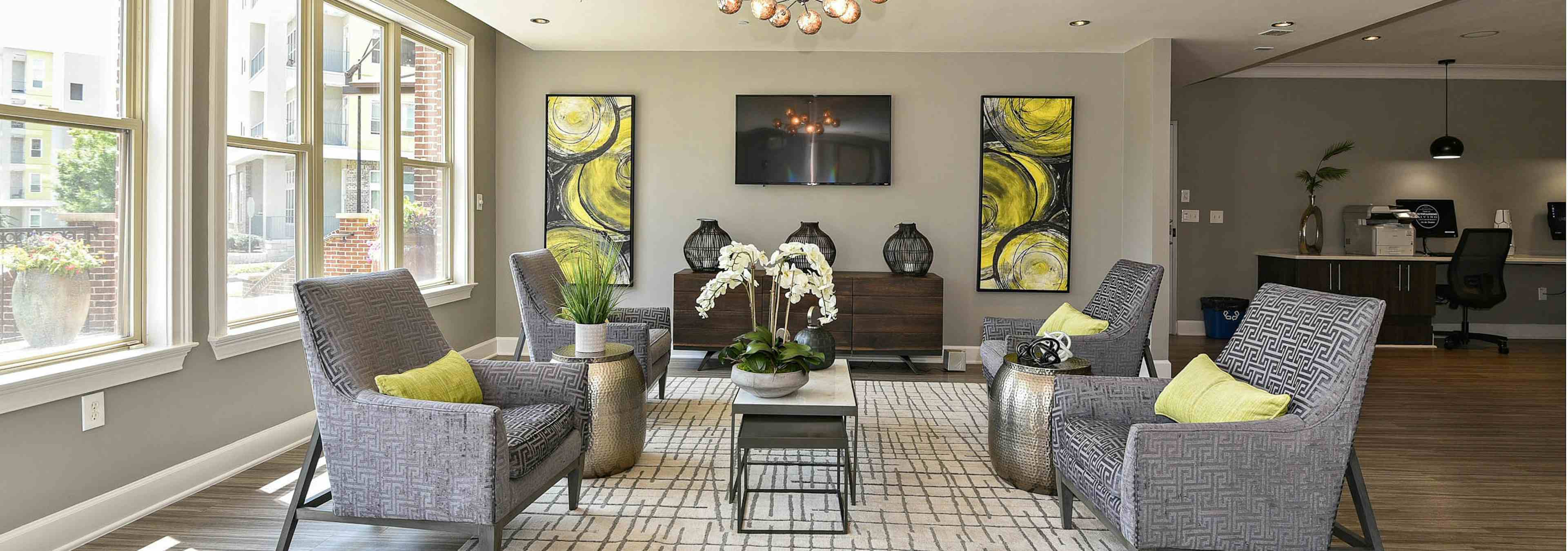 AMLI Lindbergh resident lounge with four patterned chairs and yellow decor accents with large windows facing landscape