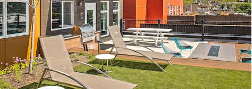 One of three rooftop decks at AMLI Wallingford with BBQ fire pit lounge seating and turf grass for lawn games