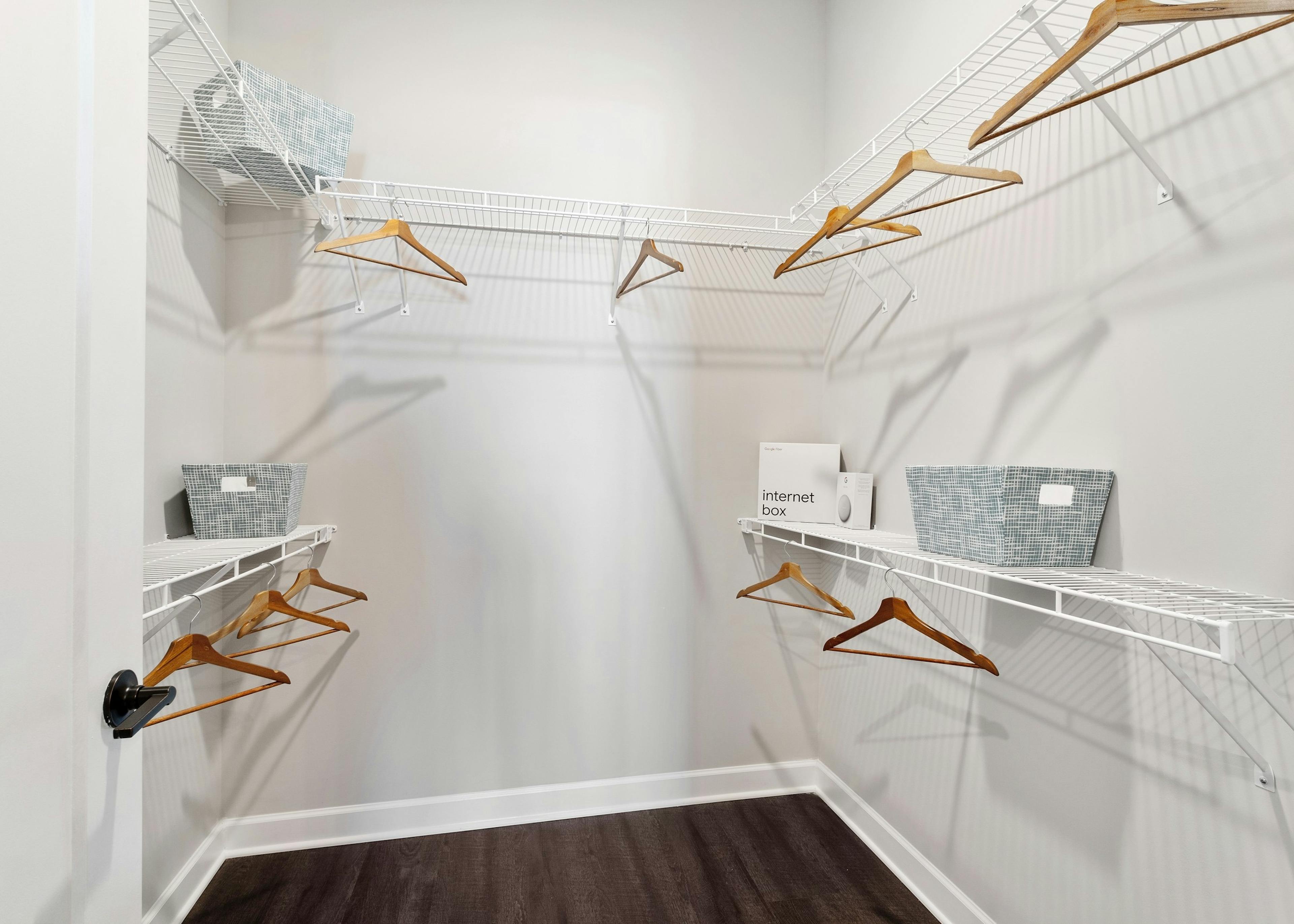 View into large bright closet with hardwood floors and white wire shelving and wooden hangers at AMLI Westside apartments 