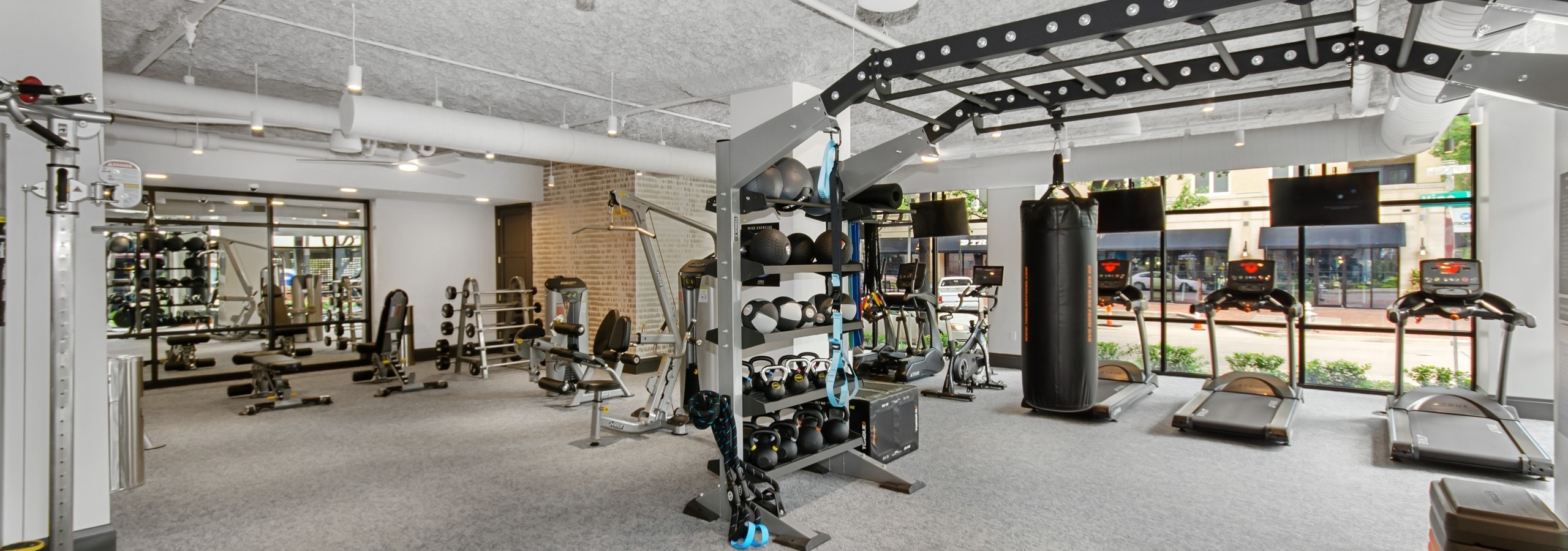 AMLI Quadrangle fitness center with a multipurpose weight training machine and treadmills facing the outside street