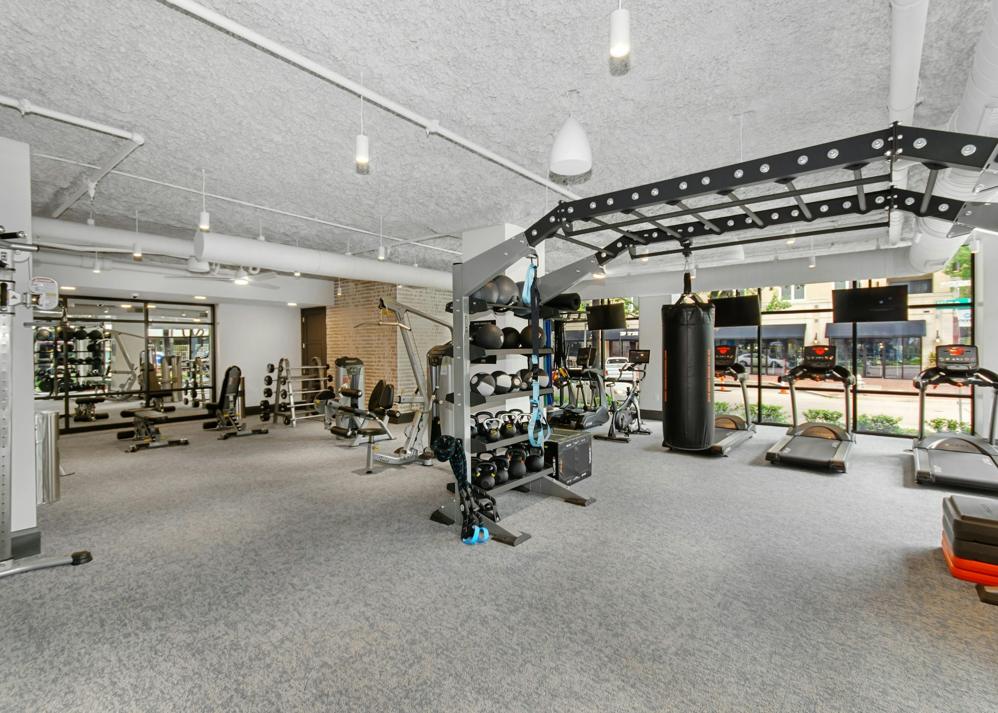 AMLI Quadrangle fitness center with a multipurpose weight training machine and treadmills facing the outside street