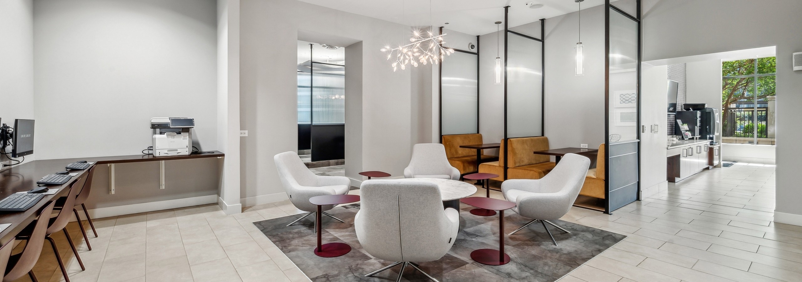 Interior view of co working space with 4 gray chairs around table and booth seating open to morning room at AMLI River North